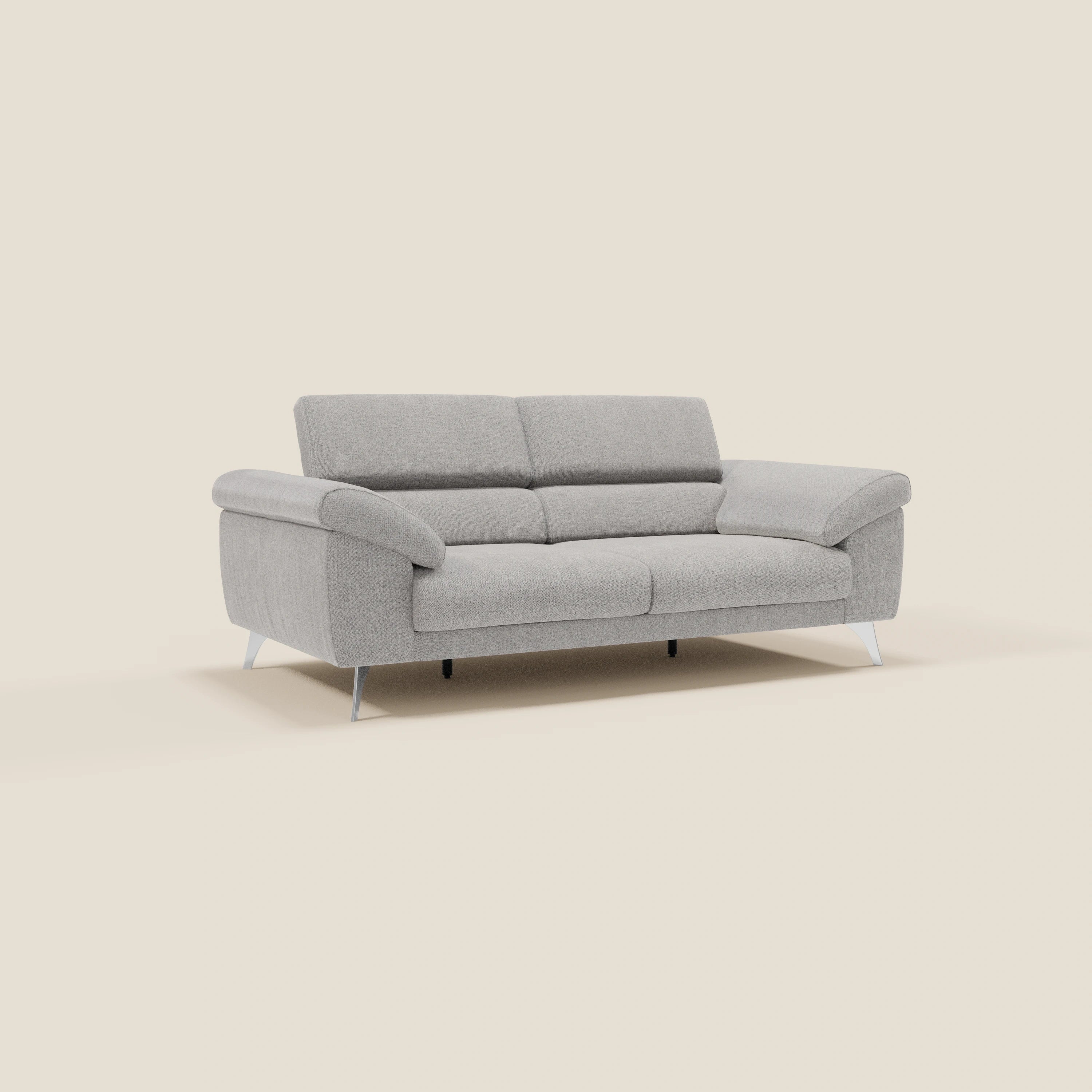 Divano moderno Donatello di Divani.Store in tessuto grigio T23 antimacchia, con poggiatesta reclinabili, sedute allungabili e braccioli portaoggetti. Il suo design elegante permette di ospitare comodamente 2-3 persone su uno sfondo bianco sporco.