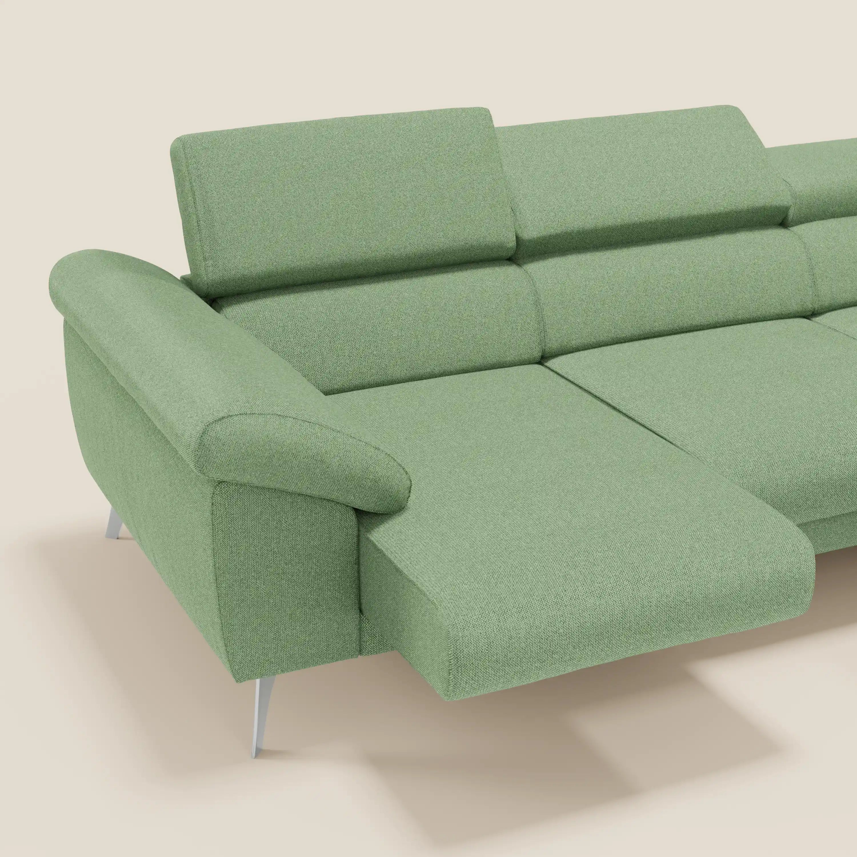 Il divano angolare Donatello di Divani.Store è caratterizzato da sedute scorrevoli, braccioli contenitore, poggiatesta in tessuto morbido smacchiabile T23 menta e gambe eleganti color argento. La chaise longue si estende a sinistra su uno sfondo bianco sporco.