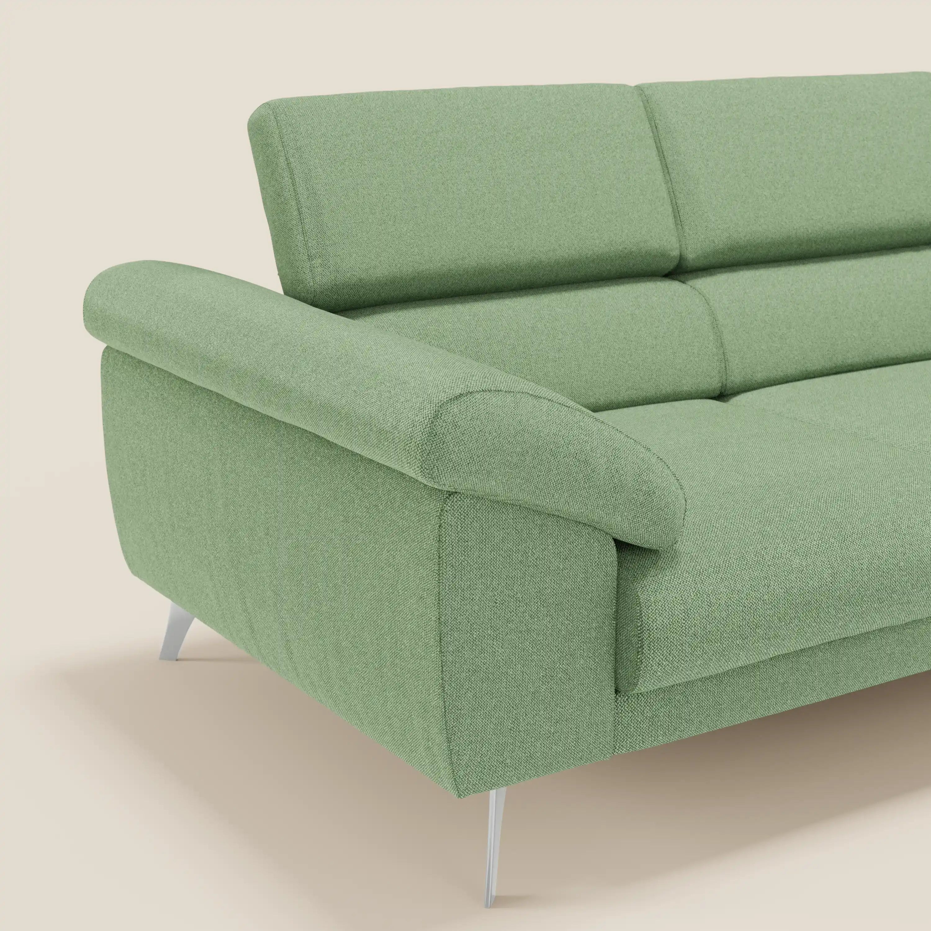 Un divano moderno Donatello di Divani.Store in tessuto smacchiabile T23 menta con 3 sedute allungabili, braccioli contenitore e poggiatesta reclinabili è mostrato ad angolo su uno sfondo beige semplice.