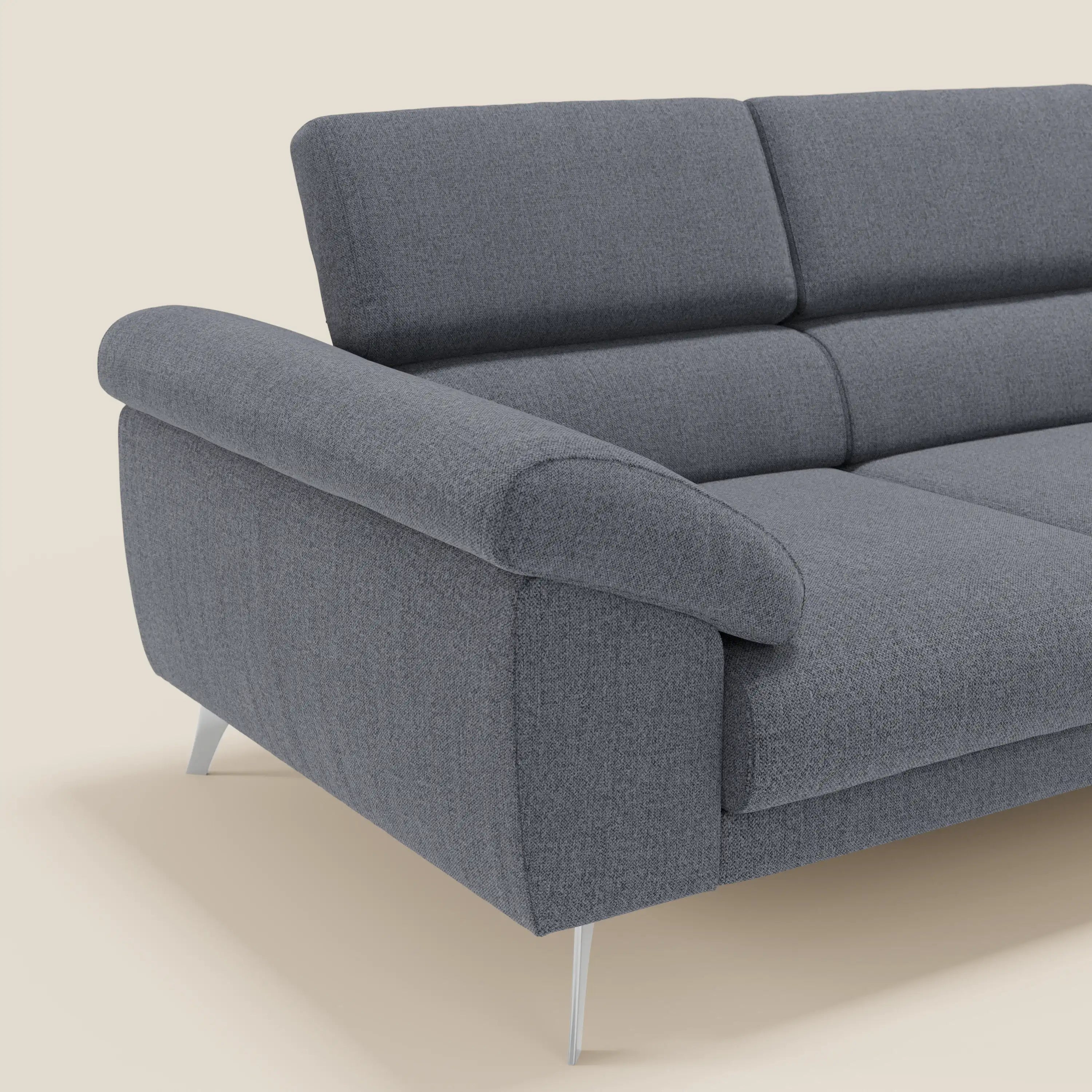 Un primo piano del divano Donatello con 3 sedute allungabili di Divani.Store in tessuto smacchiabile T23 blu grafite, con braccioli contenitore, poggiatesta reclinabili e gambe in metallo su sfondo beige; visibile solo il lato sinistro.