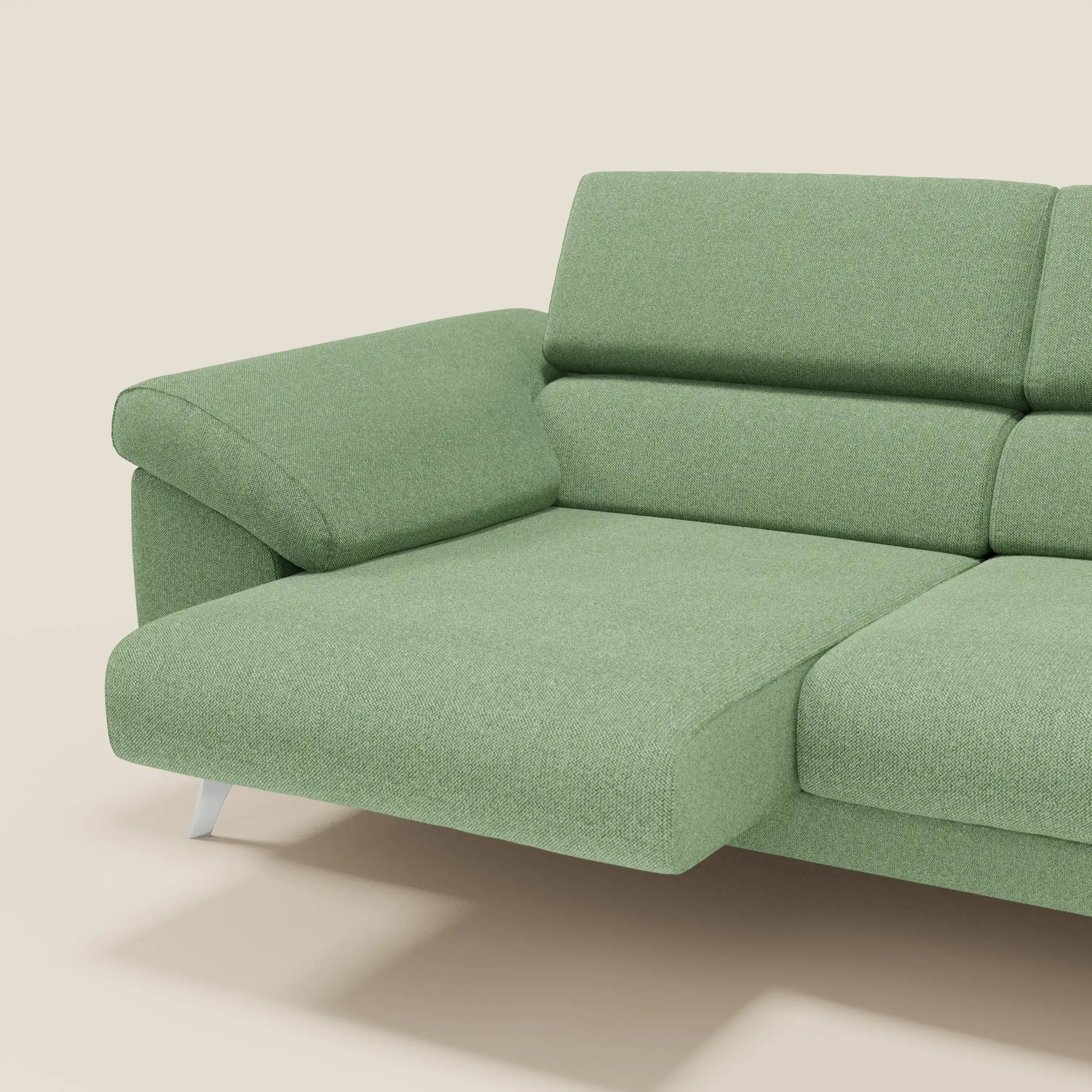 Divano moderno Donatello di Divani.Store in tessuto smacchiabile T23 menta, con sedute allungabili, braccioli contenitore e poggiatesta reclinabili. Sullo sfondo beige è visibile solo il lato sinistro allungato con gamba metallica angolata.