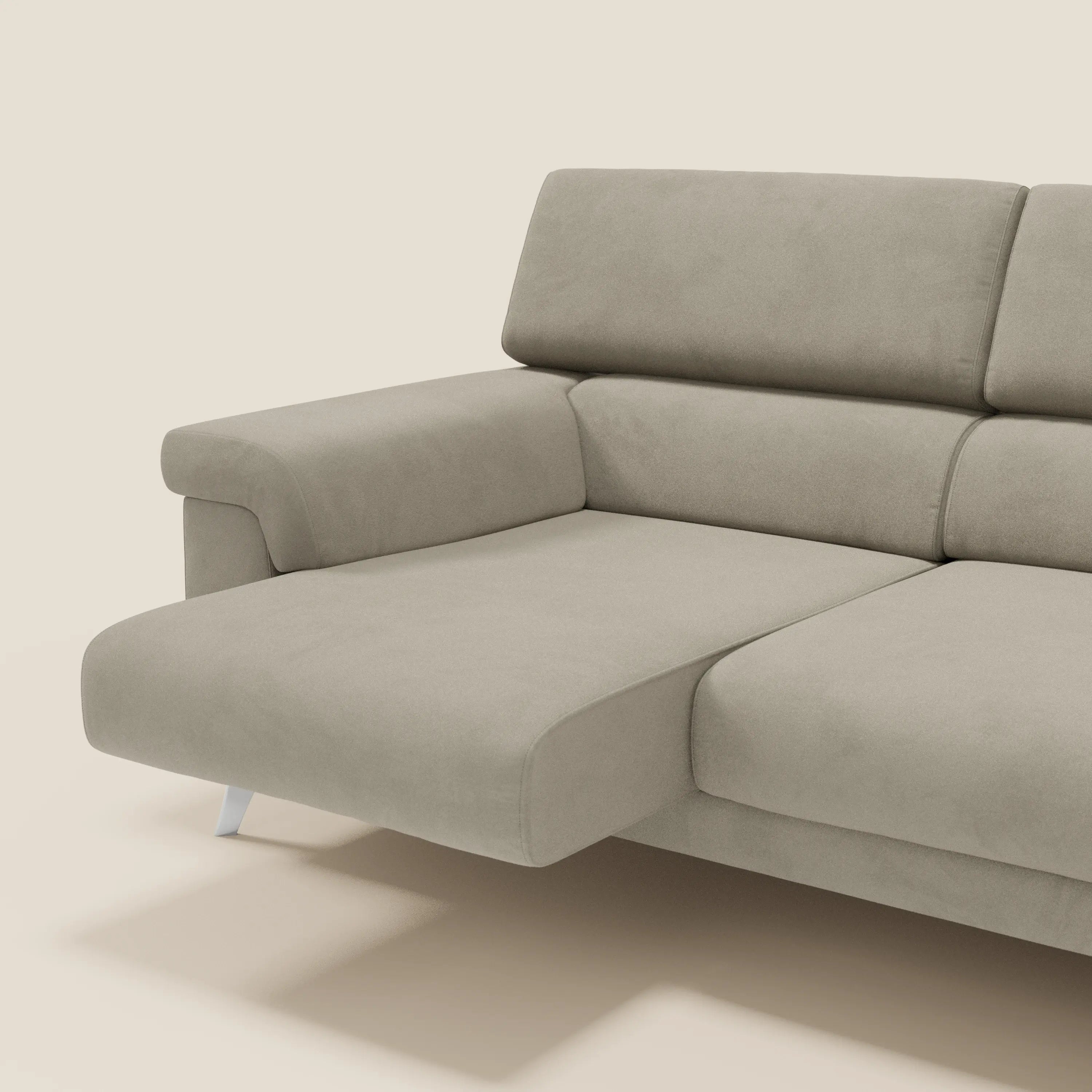 Il divano angolare Raffaello di Divani.Store è caratterizzato da sedute scorrevoli e poggiatesta regolabili in T11 tortora microfibra smacchiabile, con linee pulite, bracciolo basso, schienale imbottito e gambe in metallo argentato su sfondo beige.