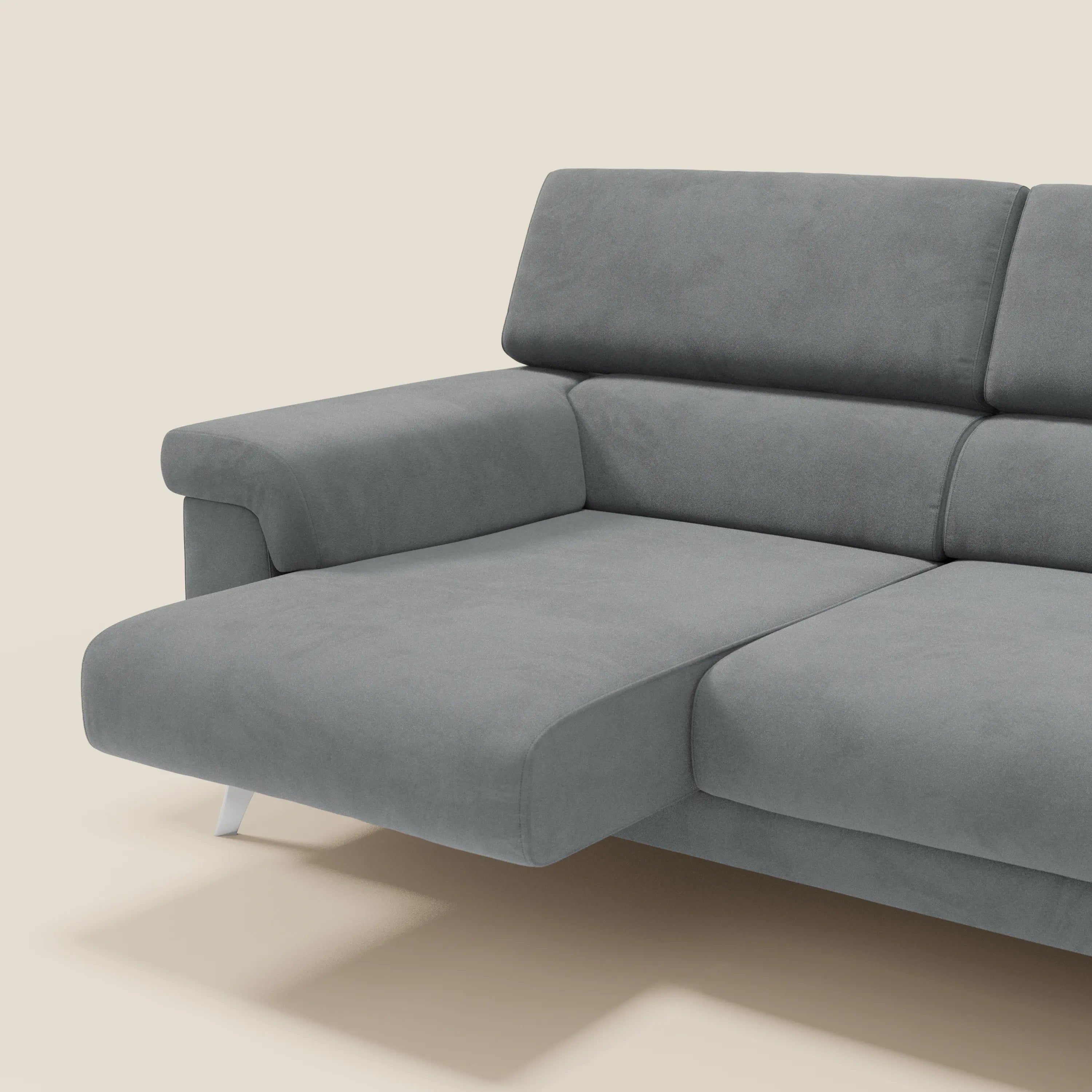 Il divano angolare Raffaello di Divani.Store è caratterizzato da sedute scorrevoli, poggiatesta regolabili e rivestimento in microfibra smacchiabile T11 grigio, con ampi braccioli e gambe metalliche angolate su sfondo beige.