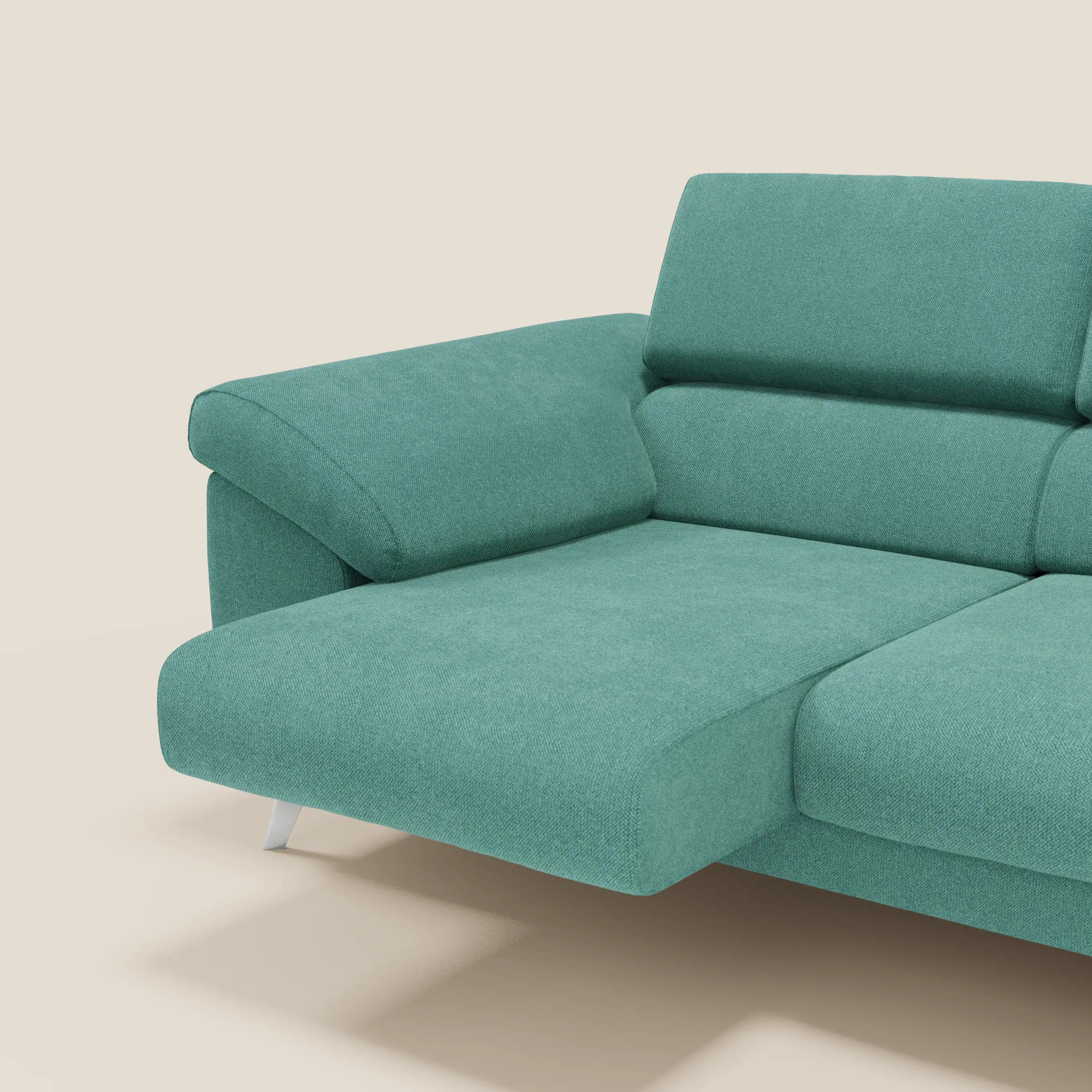 Il divano Donatello con 3 sedute allungabili di Divani.Store in tessuto smacchiabile T23 verde acqua, con braccioli contenitore e poggiatesta reclinabili, è mostrato di lato contro uno sfondo beige; visibili solo parte della seduta e dello schienale.