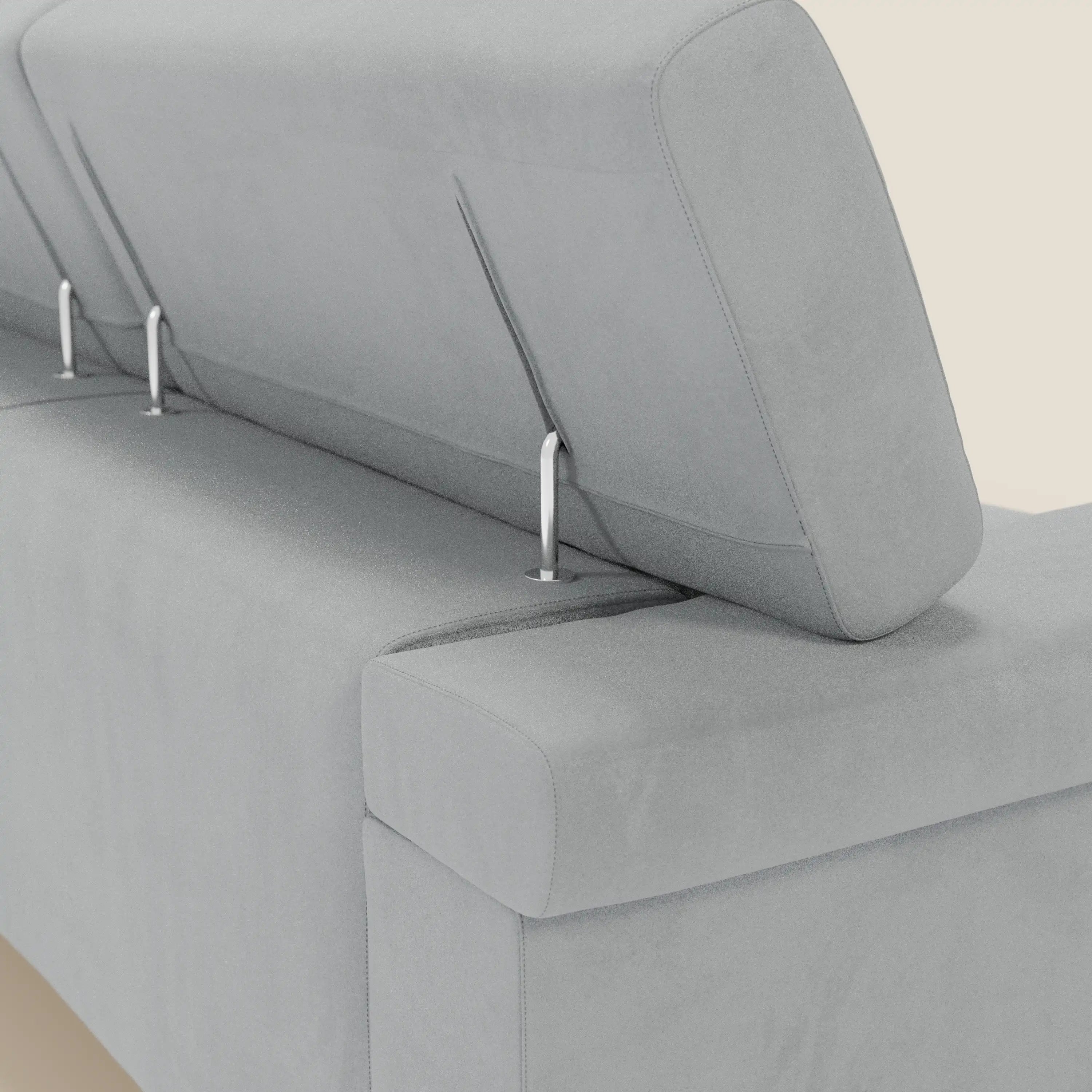 Un primo piano del Raffaello Divano angolare di Divani.Store mostra la microfibra smacchiabile T11 grigio chiaro, le sedute scorrevoli e la poggiatesta regolabile, evidenziando il design modulare con eleganti aste metalliche su uno sfondo bianco sporco.