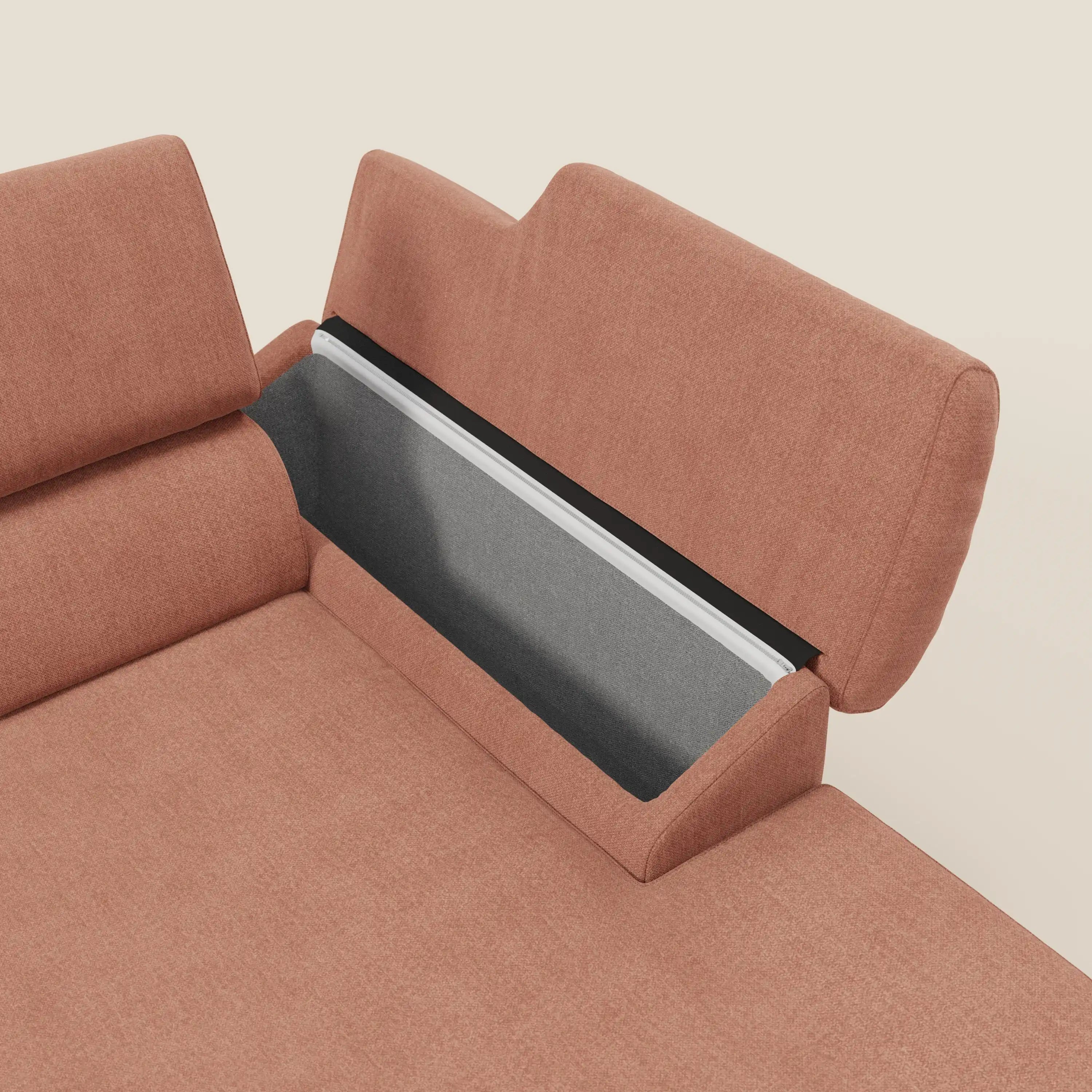 Un primo piano del Donatello Divano angolare di Divani.Store in morbido tessuto antimacchia T23 pesca mostra i sedili scorrevoli e il vano portaoggetti dello schienale rivestiti in grigio, con rivestimento rosa in tinta su schienale e sedute.