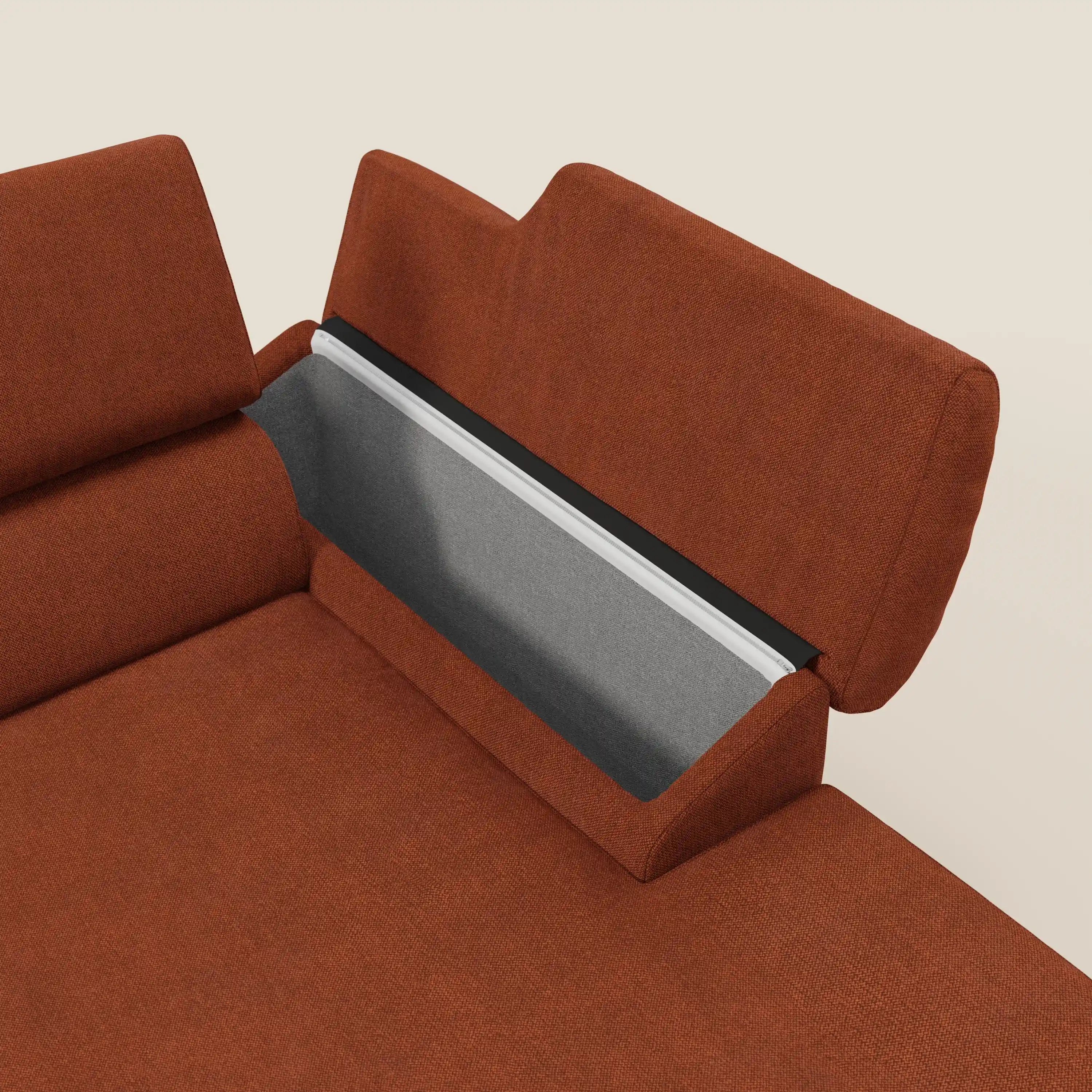 Il divano angolare Donatello di Divani.Store è caratterizzato da un tessuto antimacchia T23 arancione ruggine, sedute scorrevoli, braccioli e un vano integrato sotto lo schienale rivestito in grigio chiaro con ampio spazio. Lo sfondo è bianco sporco.