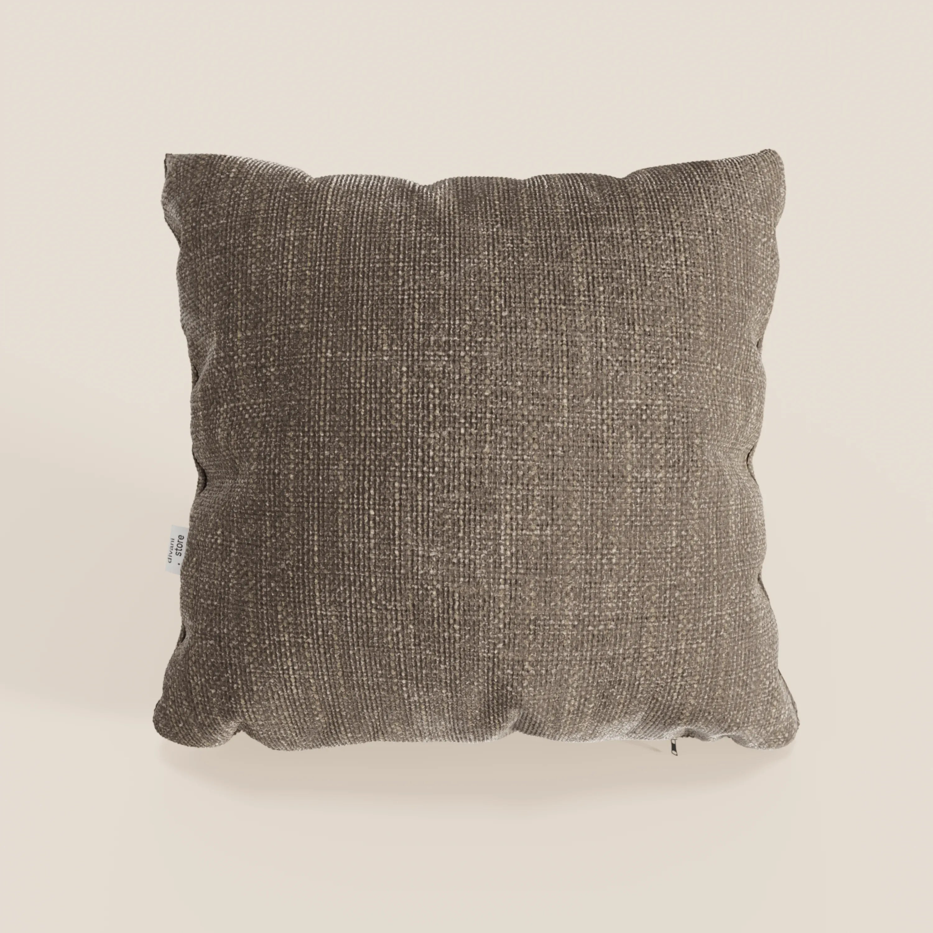 Il cuscino Lyon di Divani.Store, nel colore T06 marrone, è caratterizzato da un morbido tessuto impermeabile e da una forma quadrata leggermente rigonfia. Presentato su uno sfondo bianco sporco, include una piccola etichetta bianca sul lato sinistro per un sottile branding.