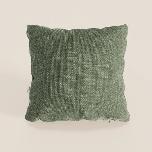 Il cuscino Lyon di Divani.Store, presentato nel colore verde testurizzato T06 (45x45 cm), è realizzato in morbido tessuto impermeabile con angoli arrotondati e una targhetta bianca sul lato sinistro, su uno sfondo beige chiaro.
