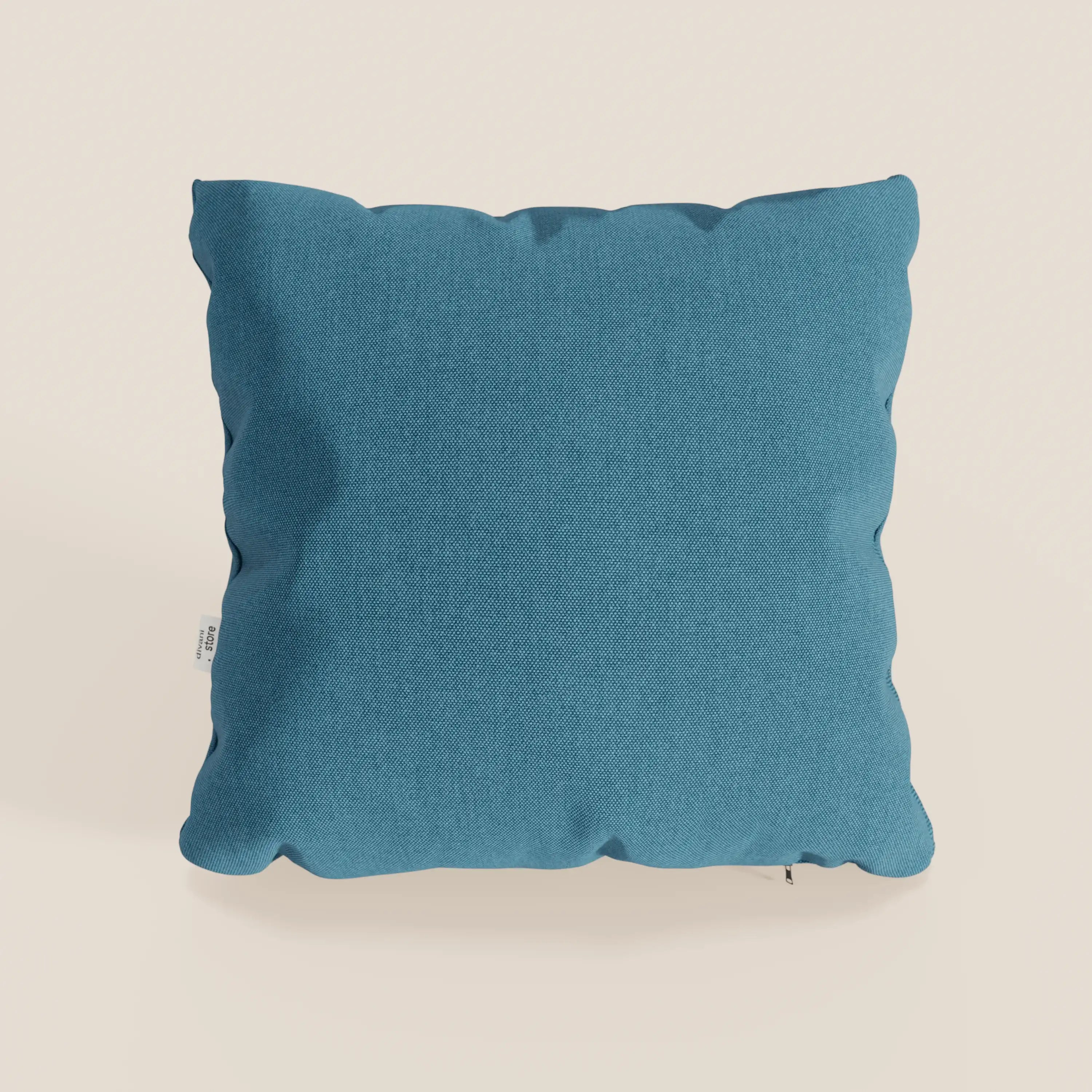 Il cuscino Honey 45x45 di Divani.Store, in azzurro impermeabile simil cotone T13, si staglia su uno sfondo bianco sporco con angoli arrotondati, pieghe sottili, etichetta bianca sul lato sinistro e fodera lavabile per una facile manutenzione.