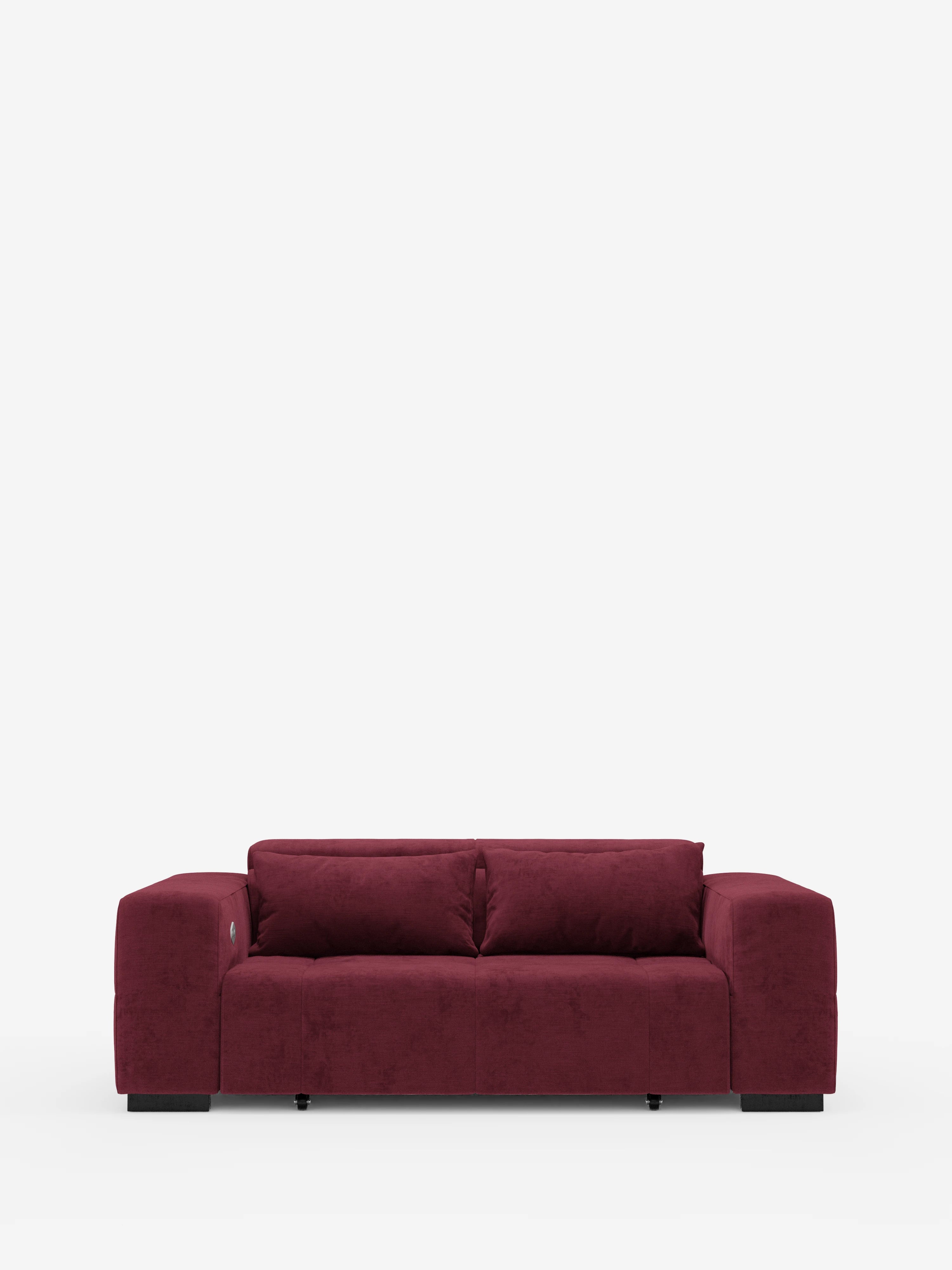 Un moderno divano Monarch rosso scuro con funzione relax elettrica per l’allungamento delle sedute e poggiatesta reclinabile, rivestito in morbido tessuto lavabile T31 di Divani.Store, caratterizzato da ampi braccioli, uno schienale basso e due cuscini di seduta, è posizionato al centro su uno sfondo bianco a tinta unita. Questo elegante divano presenta una silhouette morbida e squadrata ed è sostenuto da piccole gambe nere.