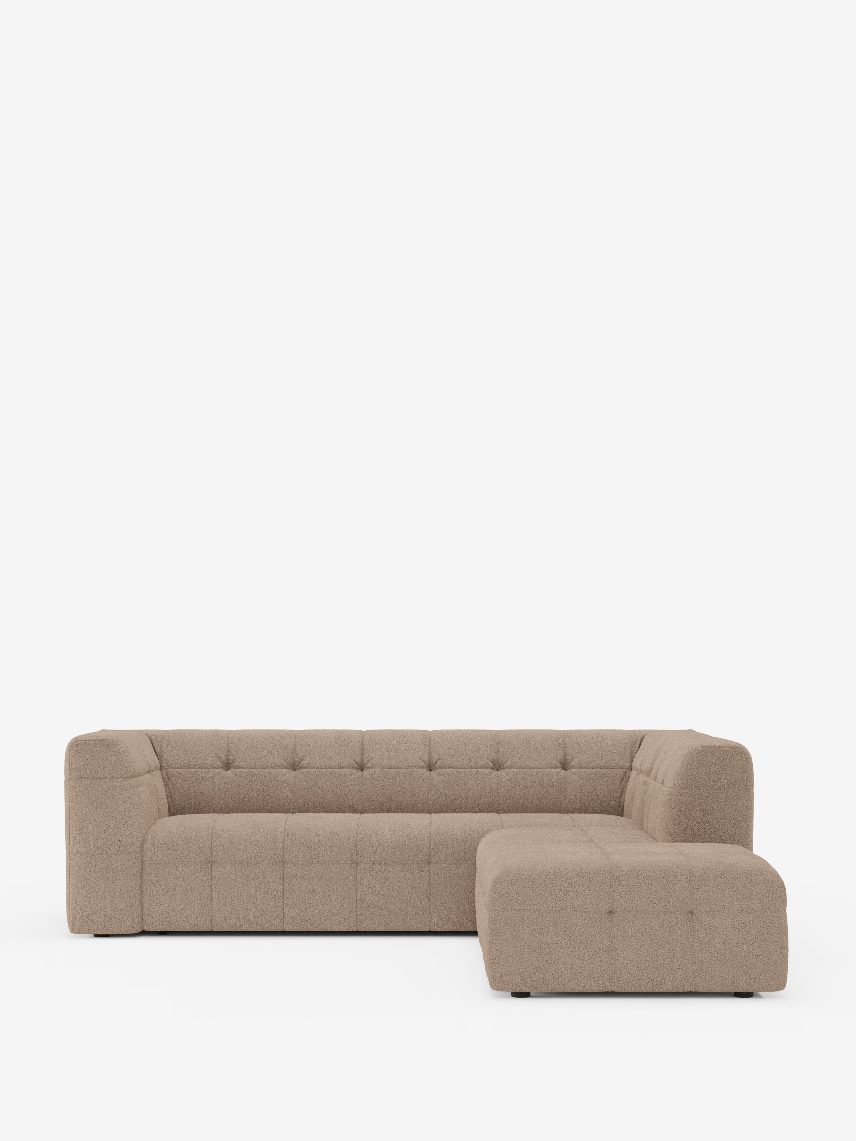Vi presentiamo il divano angolare componibile e modulare Mosaic in bouclé: capitonné e design in tessuto smacchiabile T21 di Divani.Store — un divano angolare modulare moderno, di colore marrone chiaro, con schienale basso, cuscini di seduta e schienale trapuntati (capitonné) e braccioli generosi. Il lato destro è dotato di una chaise longue. Il rivestimento in bouclé conferisce una texture delicata, che risalta sullo sfondo bianco a tinta unita.
