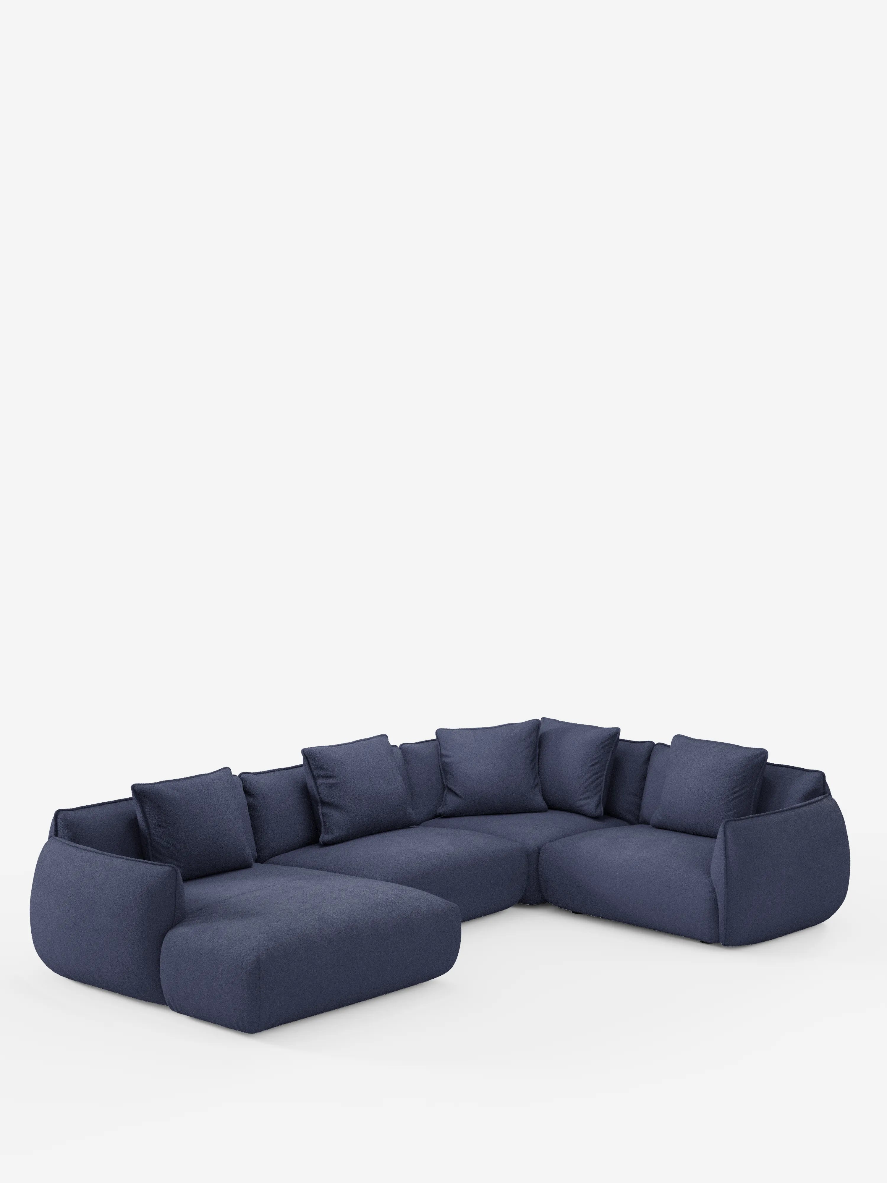 Su uno sfondo bianco a tinta unita spicca un ampio divano angolare panoramico componibile Nimbus, color blu scuro, con penisola e angolo in tessuto smacchiabile T33 di Divani.Store. Questo divano componibile moderno e accogliente si caratterizza per i cuscini e i cuscini dello schienale morbidi e ben imbottiti, i bordi arrotondati e l’assenza di gambe a vista, incarnando alla perfezione l’eleganza dell’artigianato Made in Italy.