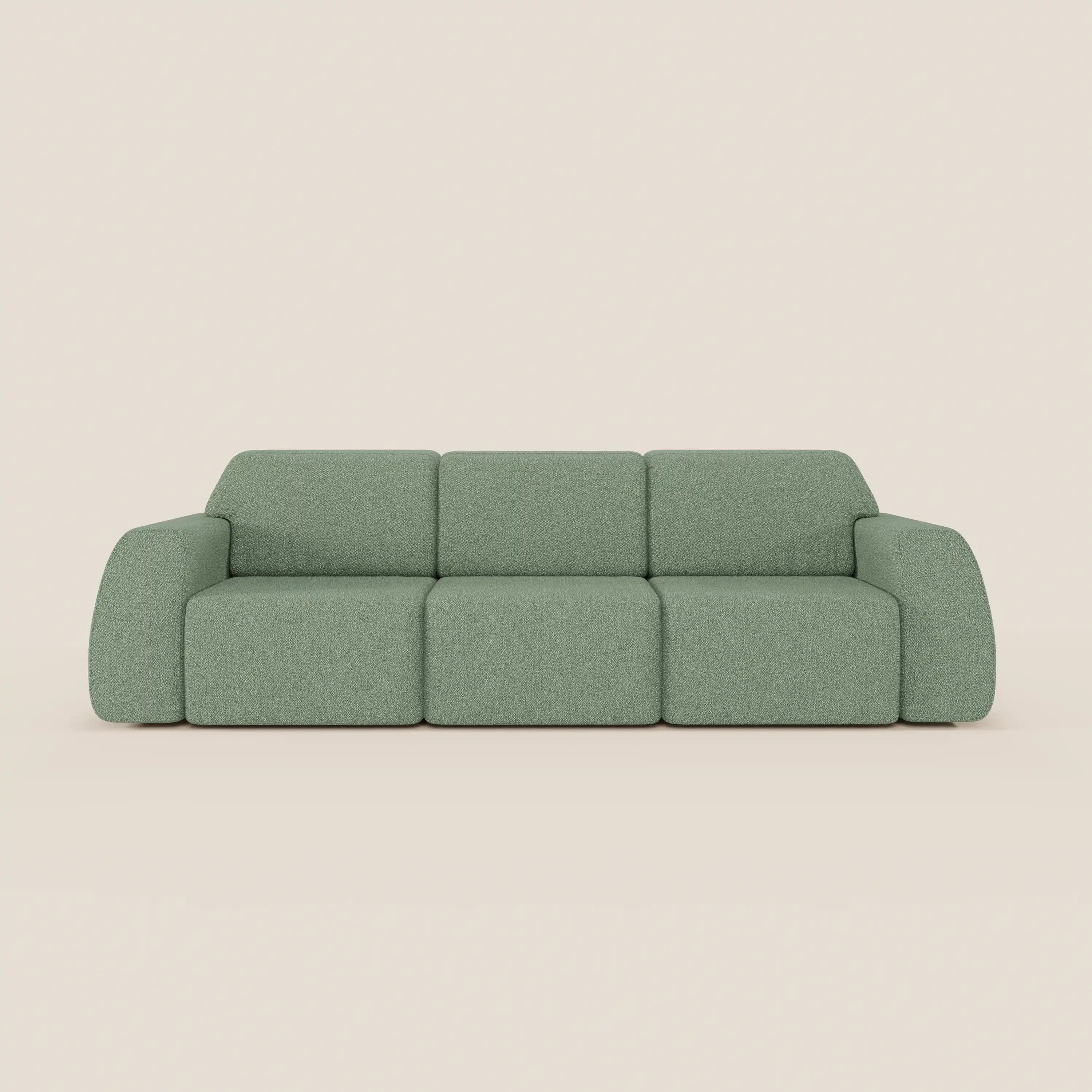 Il divano Orbit con 3 sedute scorrevoli e allungabili in tessuto effetto cotone smacchiabile T33 di Divani.Store, in verde salvia con ampi braccioli e cuscini di seduta a blocchi, si staglia su uno sfondo beige. Il morbido tessuto ha un aspetto leggermente strutturato.