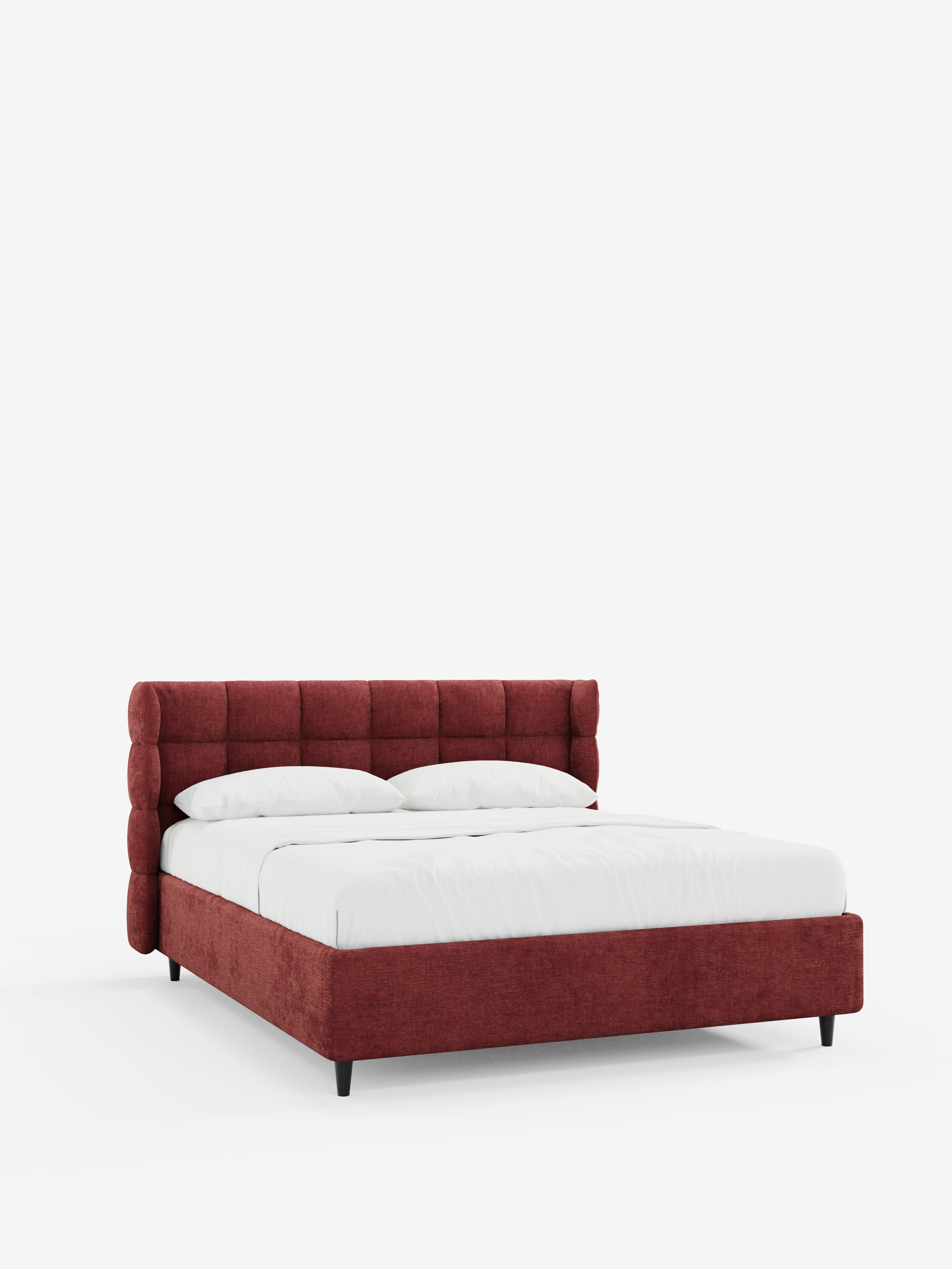 Un moderno letto imbottito RAGNAR dal profilo basso, con contenitore e testiera capitonné avvolgente, realizzato da Letti.store in tessuto rosso intenso certificato Oeko-Tex®, caratterizzato da struttura e testiera imbottite, biancheria da letto bianca, due cuscini e gambe corte nere. Il letto è presentato su uno sfondo bianco a tinta unita per mettere in risalto il suo design pulito e contemporaneo.