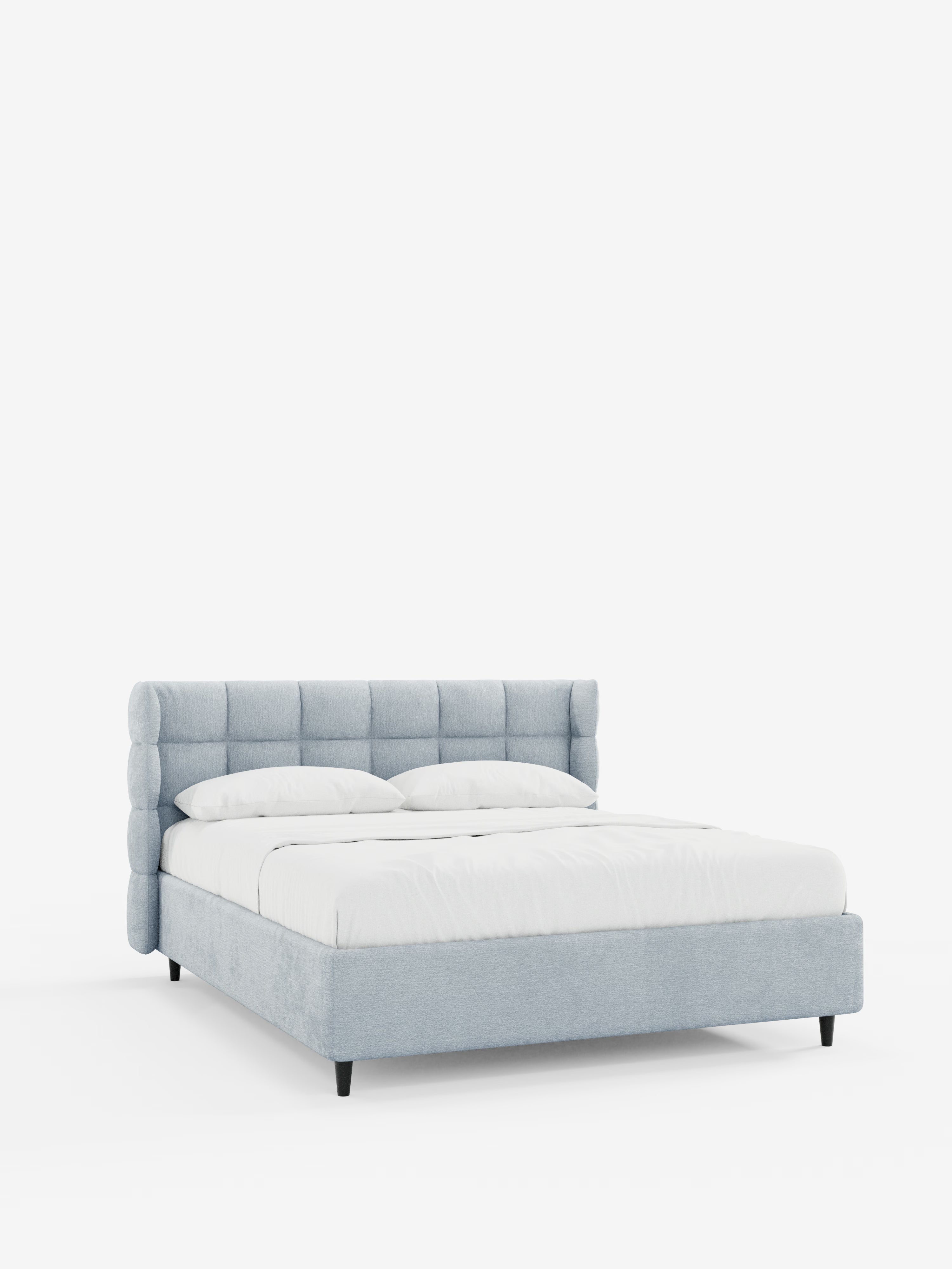 Il letto imbottito RAGNAR con contenitore e testiera capitonné avvolgente di Letti.store presenta un design moderno e minimalista con un elegante rivestimento grigio chiaro certificato Oeko-Tex®. La sua raffinata testiera capitonné è di forma cilindrica e trapuntata, mentre la struttura a profilo ribassato poggia su corte gambe nere. Il letto è abbellito da biancheria da letto candida e due cuscini, che risaltano su uno sfondo bianco a tinta unita.