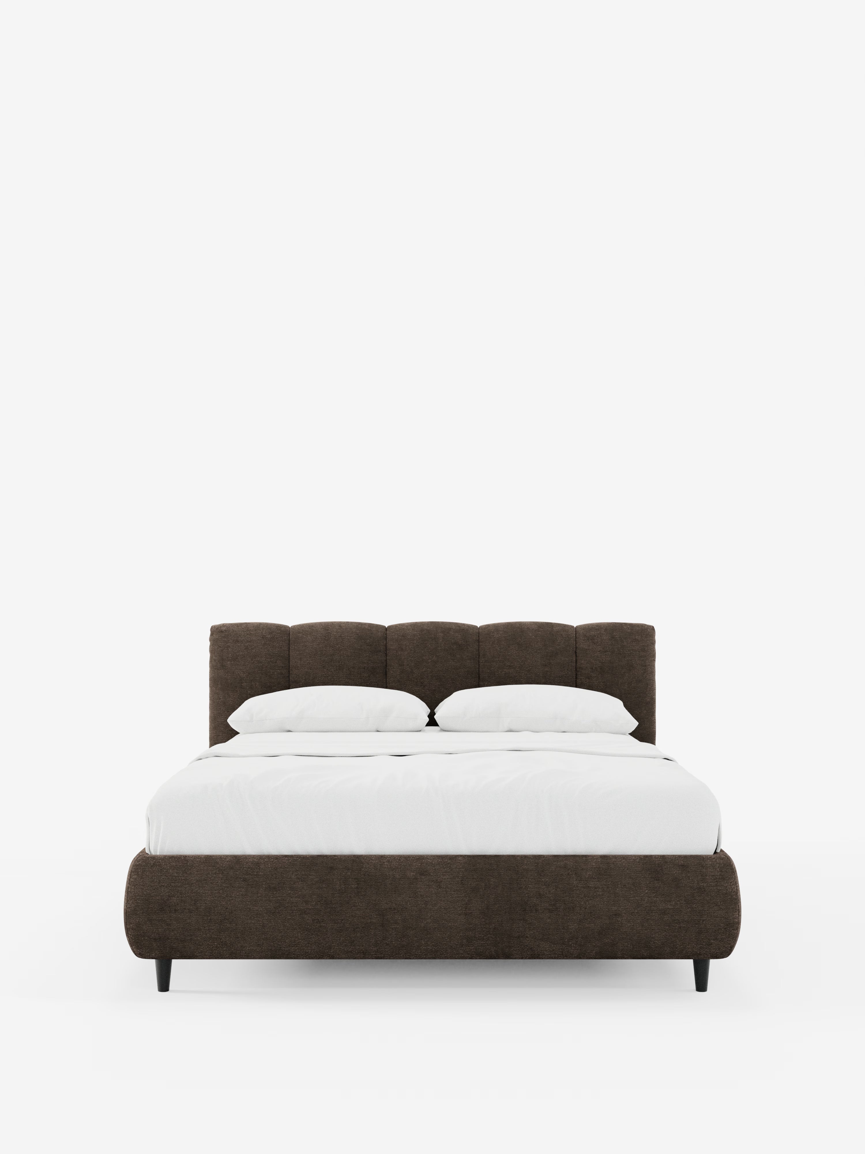 Viene presentato il letto imbottito ARKAM con contenitore e testiera a cuciture verticali di Letti.store, caratterizzato da una struttura in tessuto marrone certificato Oeko-Tex® con testiera imbottita e cuciture verticali. Il letto è rivestito con biancheria da letto bianca e due cuscini, poggia su corte gambe nere ed è posizionato al centro di uno sfondo bianco a tinta unita.