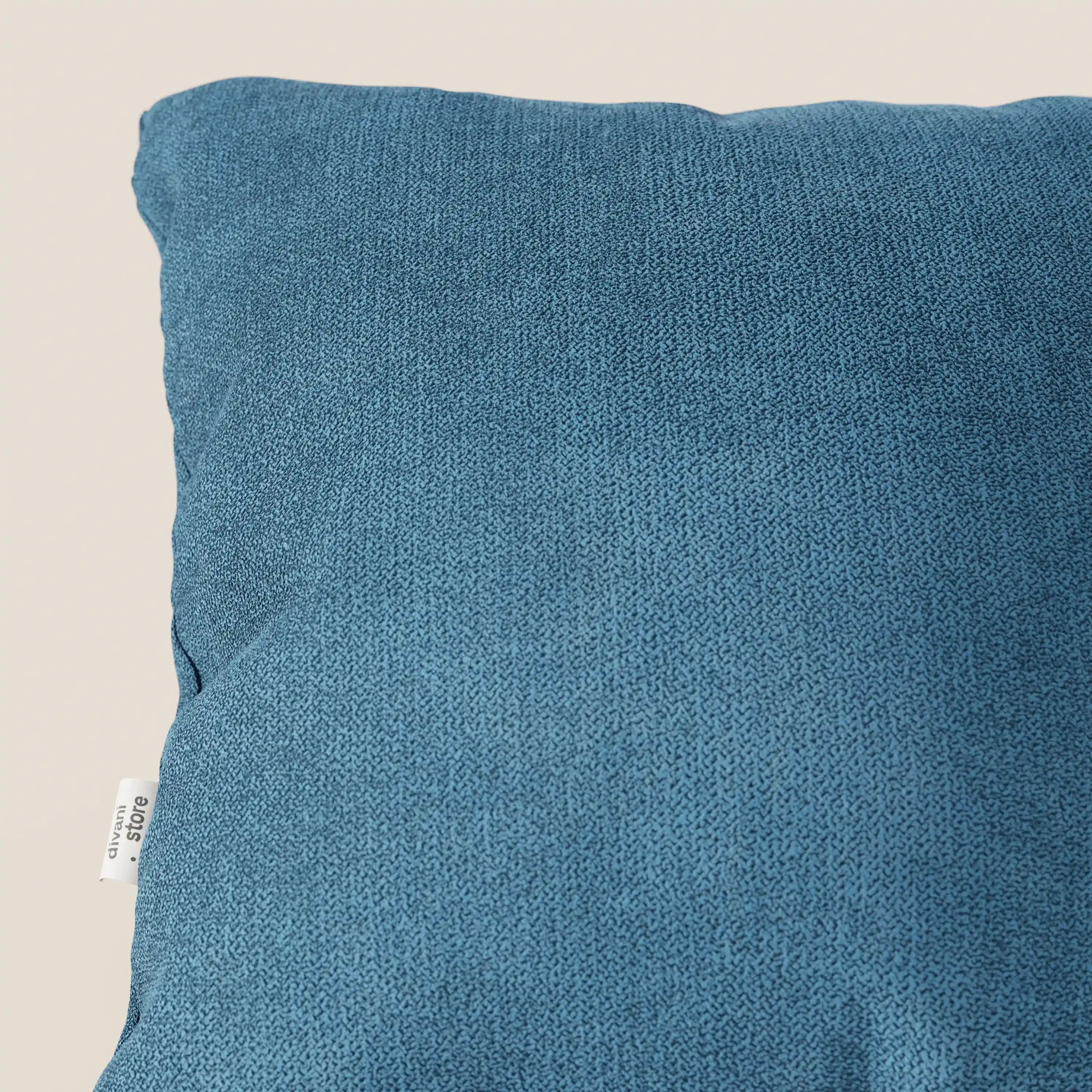Primo piano del cuscino Destiny 45x45 cm di Divani.Store, in tessuto morbido impermeabile T02 azzurro, su sfondo beige chiaro. Una piccola etichetta bianca è attaccata alla cucitura, evidenziandone l'elegante consistenza e i dettagli.