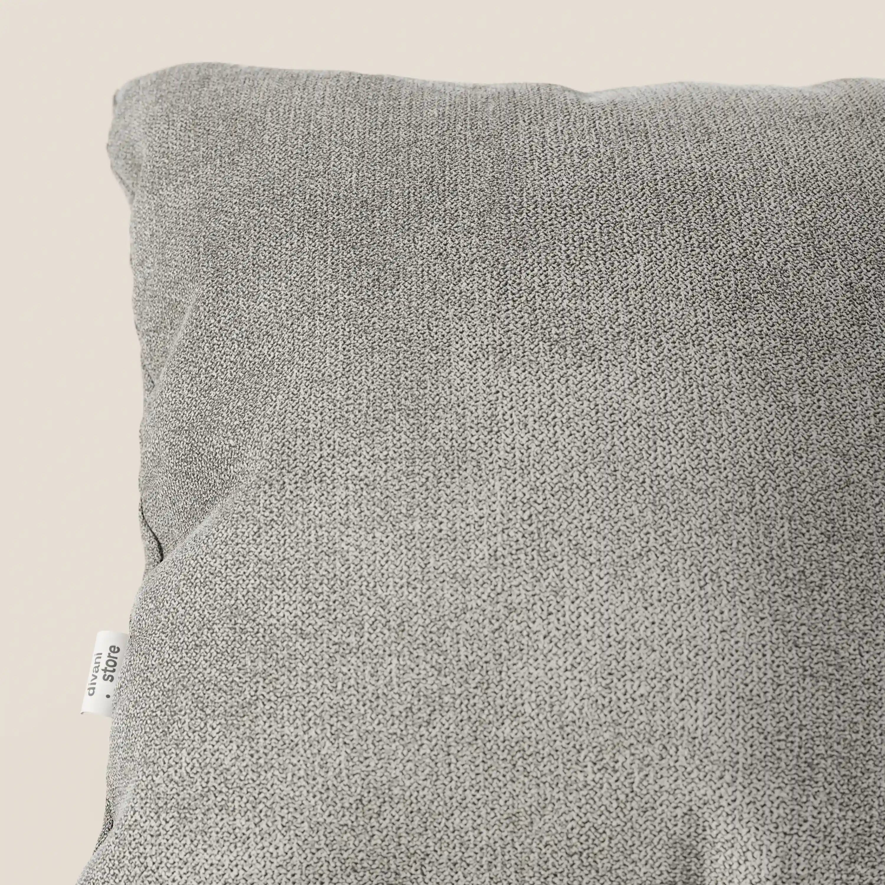 Un primo piano del cuscino Destiny 45x45 cm di Divani.Store, disponibile in diversi colori e realizzato in tessuto morbido impermeabile T02 beige, con una piccola etichetta bianca sul bordo sinistro, riempie gran parte dello sfondo beige.