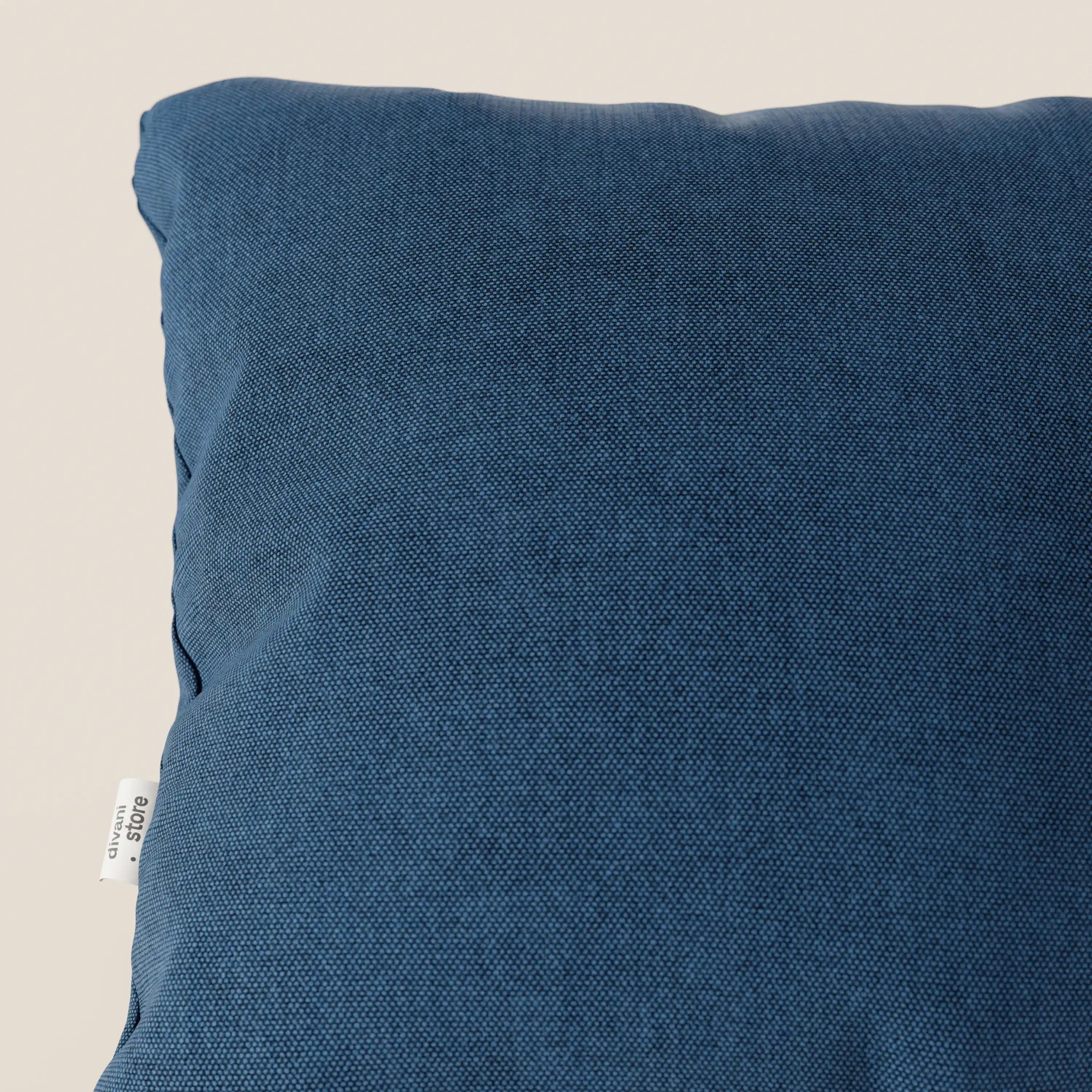 Primo piano del cuscino Honey 45x45 di Divani.Store, presentato in tessuto blu T13 impermeabile simil-cotone con superficie strutturata e piccola etichetta laterale bianca, pratico ed elegante su uno sfondo beige chiaro.