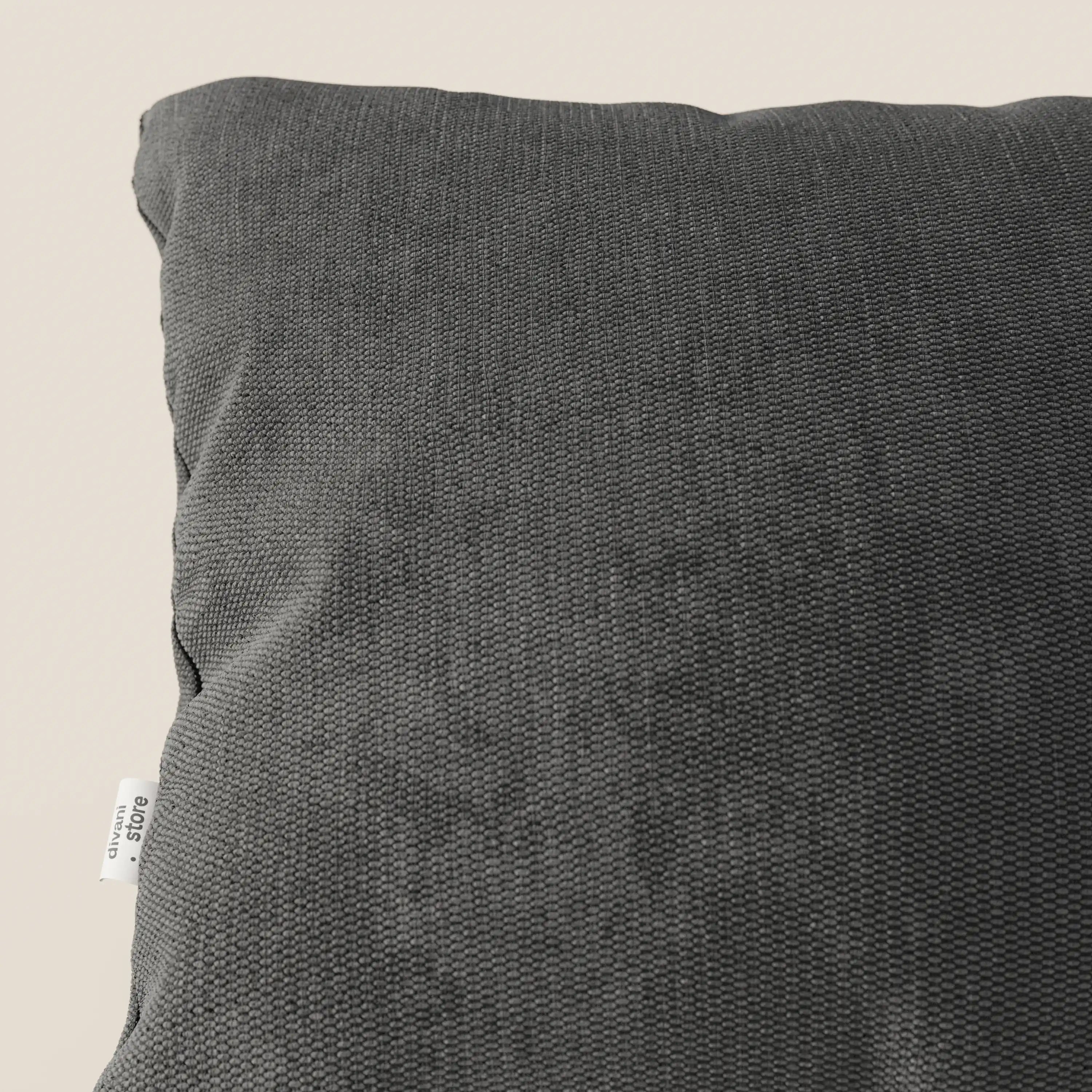 Primo piano del cuscino Miami di Divani.Store in morbido tessuto impermeabile T14 antracite, con piccola etichetta bianca e testo nero, che spicca su un morbido sfondo beige chiaro.