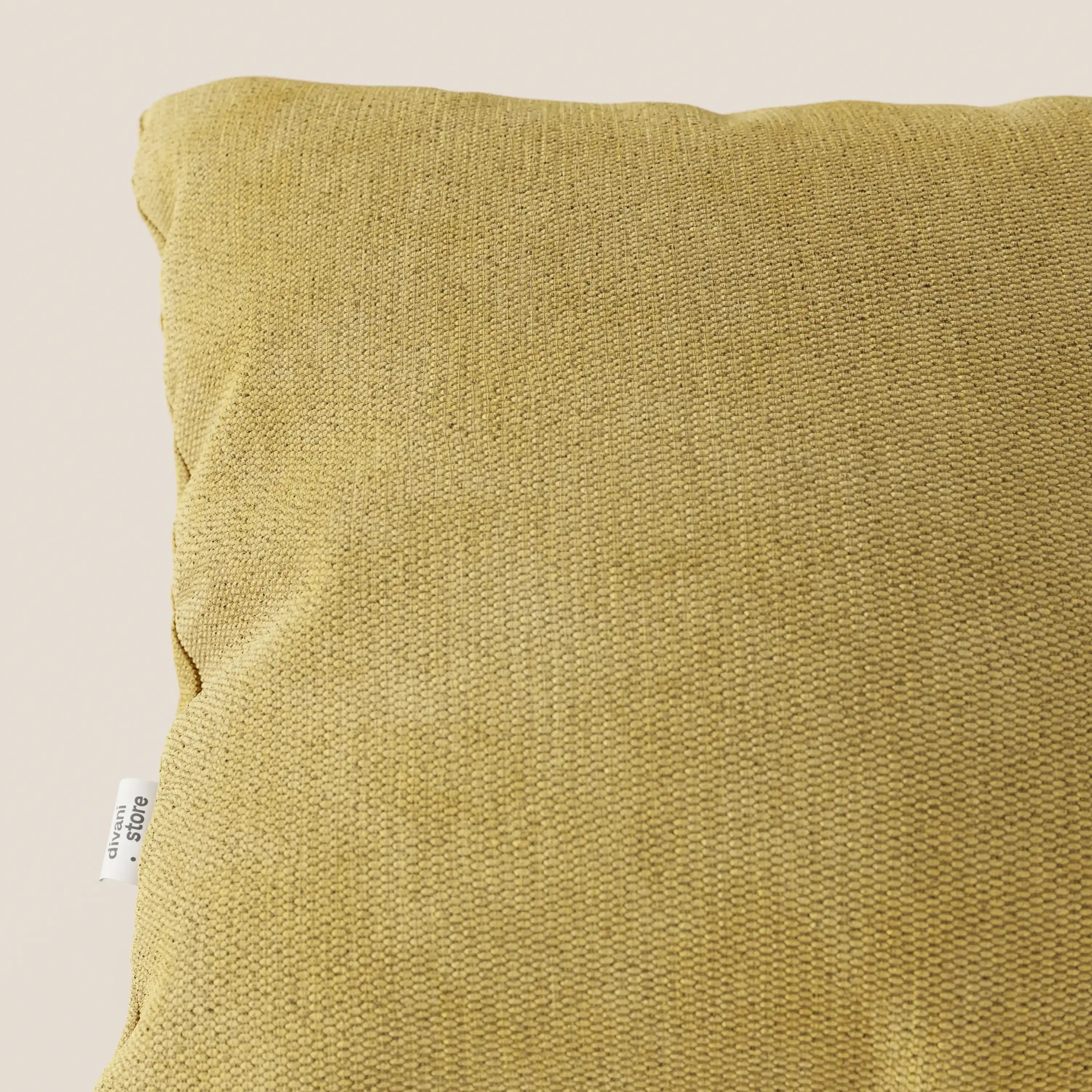 Primo piano del cuscino Miami 45x45 cm di Divani.Store, in morbido tessuto impermeabile T14 giallo con etichetta "urban" bianca, su sfondo neutro. Di questo cuscino è visibile solo la parte superiore sinistra.