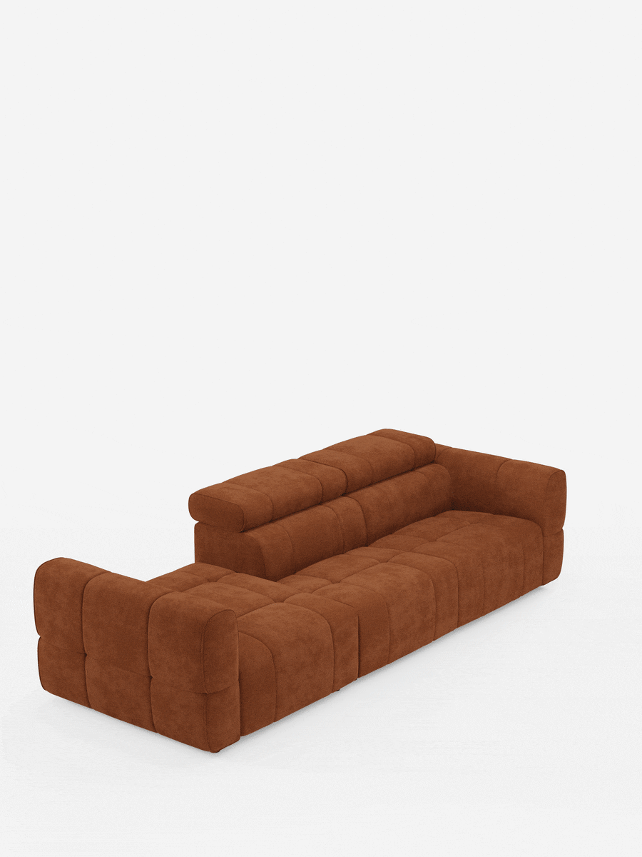 Un divano componibile Giotto color ruggine con terminale aperto - opzione relax elettrico in tessuto smacchiabile T23, caratterizzato da un design a blocchi modulari trapuntati con una lunga sezione principale e una chaise longue sul lato sinistro su uno sfondo bianco a tinta unita.