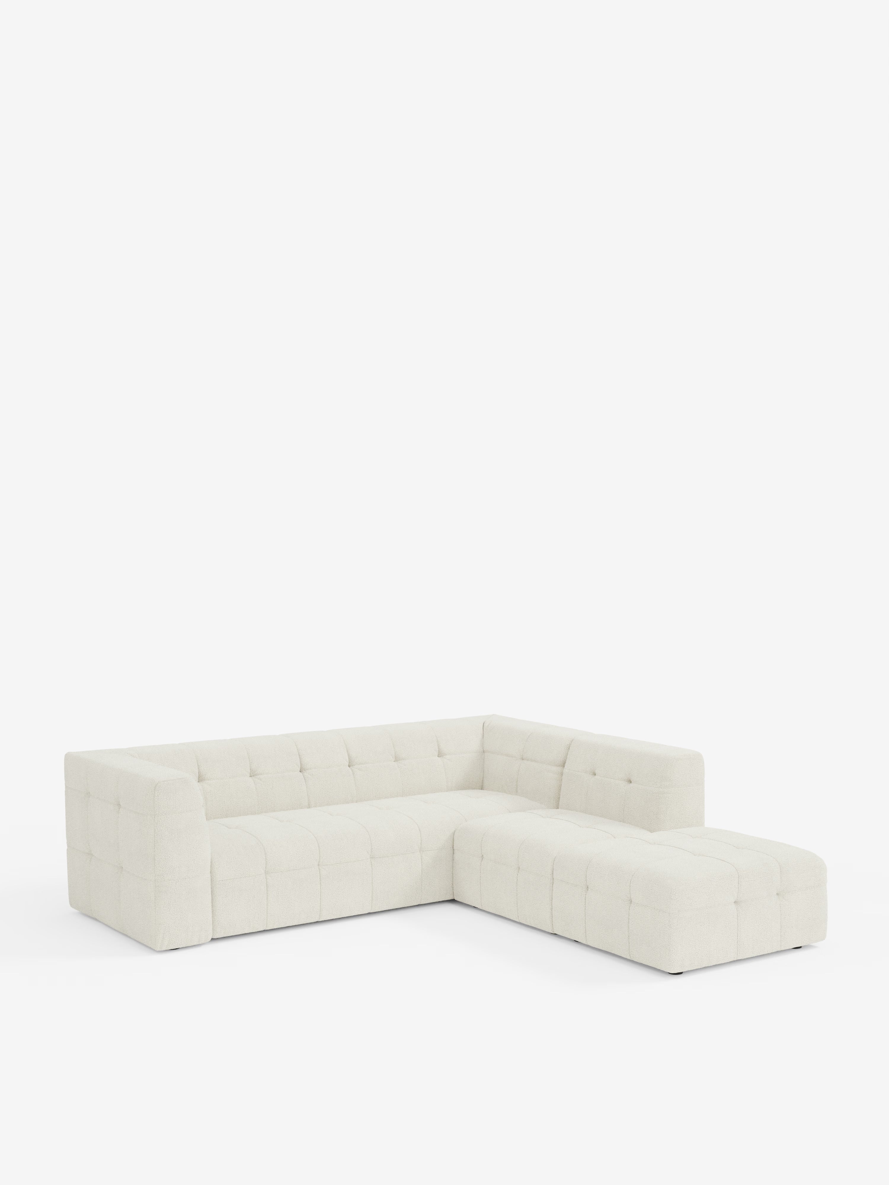 Un moderno divano angolare componibile e modulare in tessuto bouclé smacchiabile T21, modello Mosaic di Divani.Store, caratterizzato da un design capitonné e da linee pulite. Perfetto per un soggiorno moderno, questo divano presenta una chaise longue sulla destra e uno schienale basso, ed è presentato su uno sfondo bianco neutro.