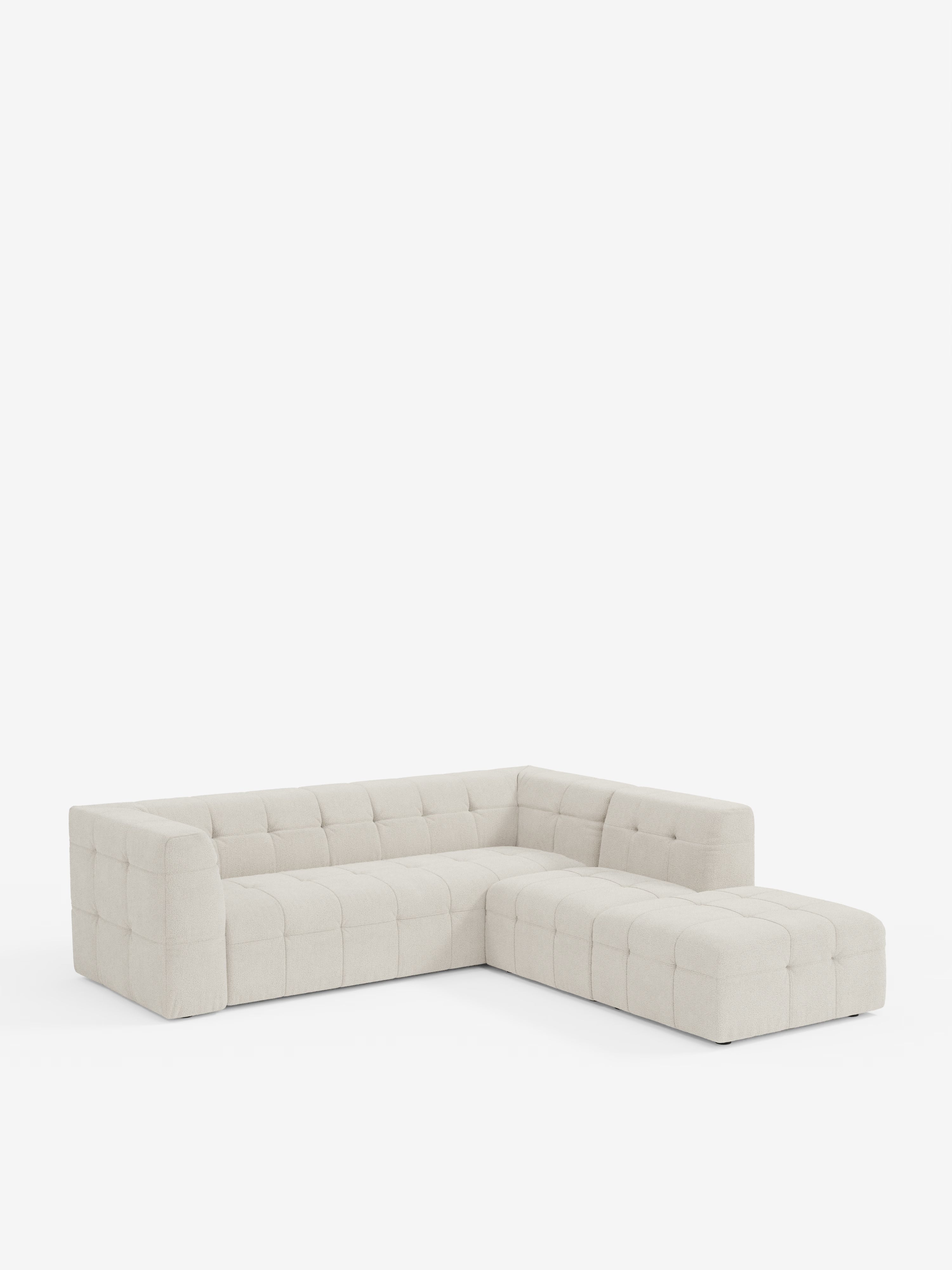 Un moderno divano angolare componibile e modulare Mosaic a forma di L di Divani.Store, realizzato in tessuto bouclé T21 beige chiaro e resistente alle macchie, con rivestimento capitonné trapuntato, braccioli bassi e squadrati e chaise longue orientata a destra. Presentato su uno sfondo bianco a tinta unita per mettere in risalto il design pulito e minimalista del divano.