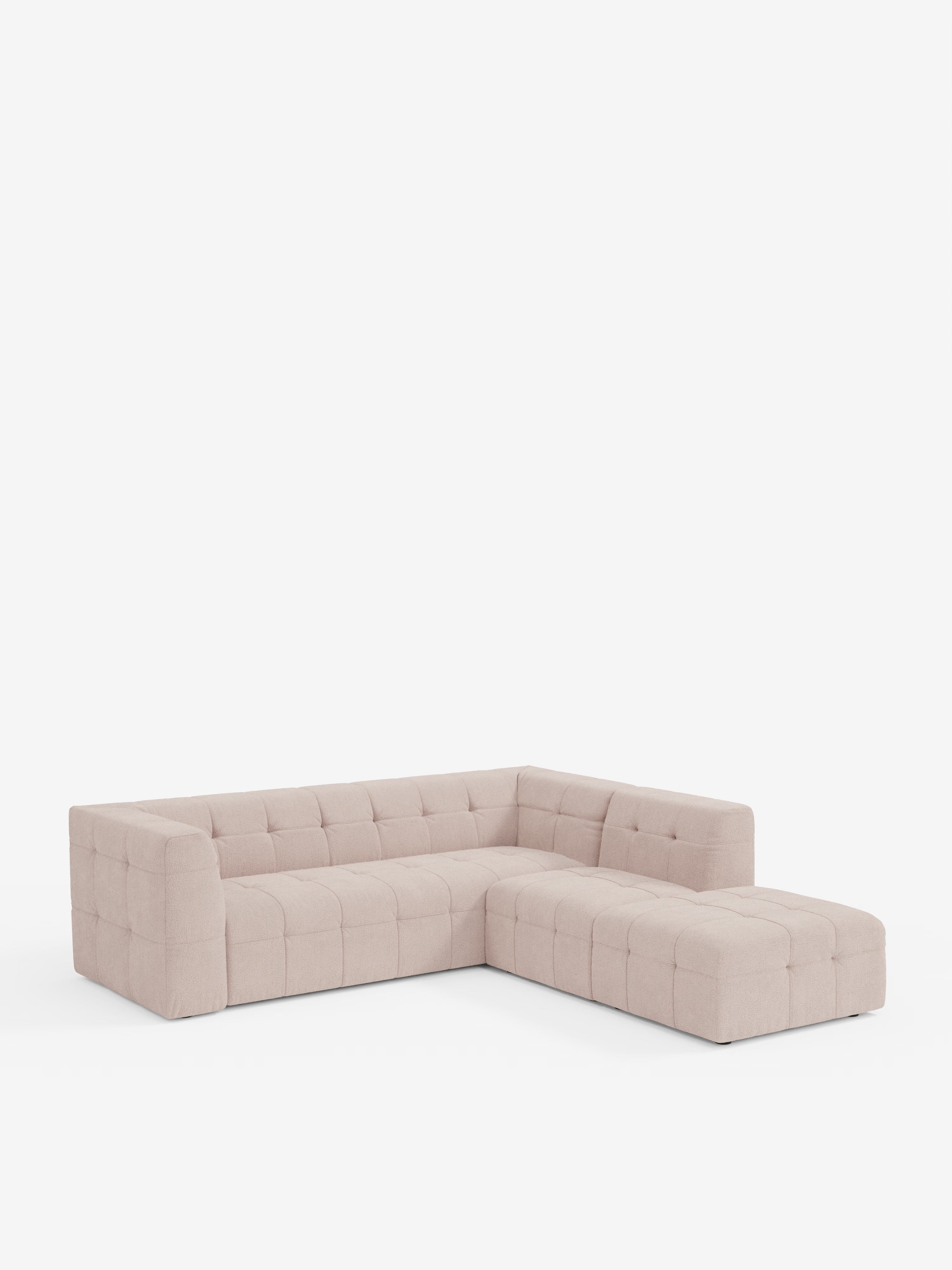 Il divano angolare componibile e modulare Mosaic di Divani.Store, in bouclé, è presentato in una versione moderna color beige chiaro, con rivestimento capitonné e schienale basso, su uno sfondo bianco a tinta unita. Il design è caratterizzato da linee pulite, morbidi cuscini in tessuto bouclé T21, morbido e resistente alle macchie, e dall’assenza di gambe a vista, che conferiscono al divano un aspetto minimalista e accogliente.