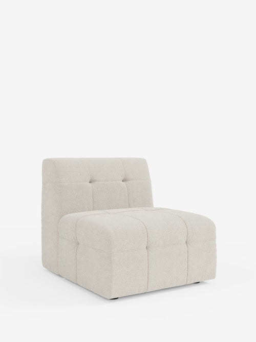 La poltrona Mosaic modulo da 77 cm in bouclé di Divani.Store presenta un design moderno senza braccioli, con schienale e seduta trapuntati, rivestiti in tessuto T21 beige chiaro e resistente alle macchie. Con il suo profilo basso e squadrato e senza gambe a vista, questa poltrona decorativa poggia direttamente sul pavimento, messa in risalto da uno sfondo bianco a tinta unita.