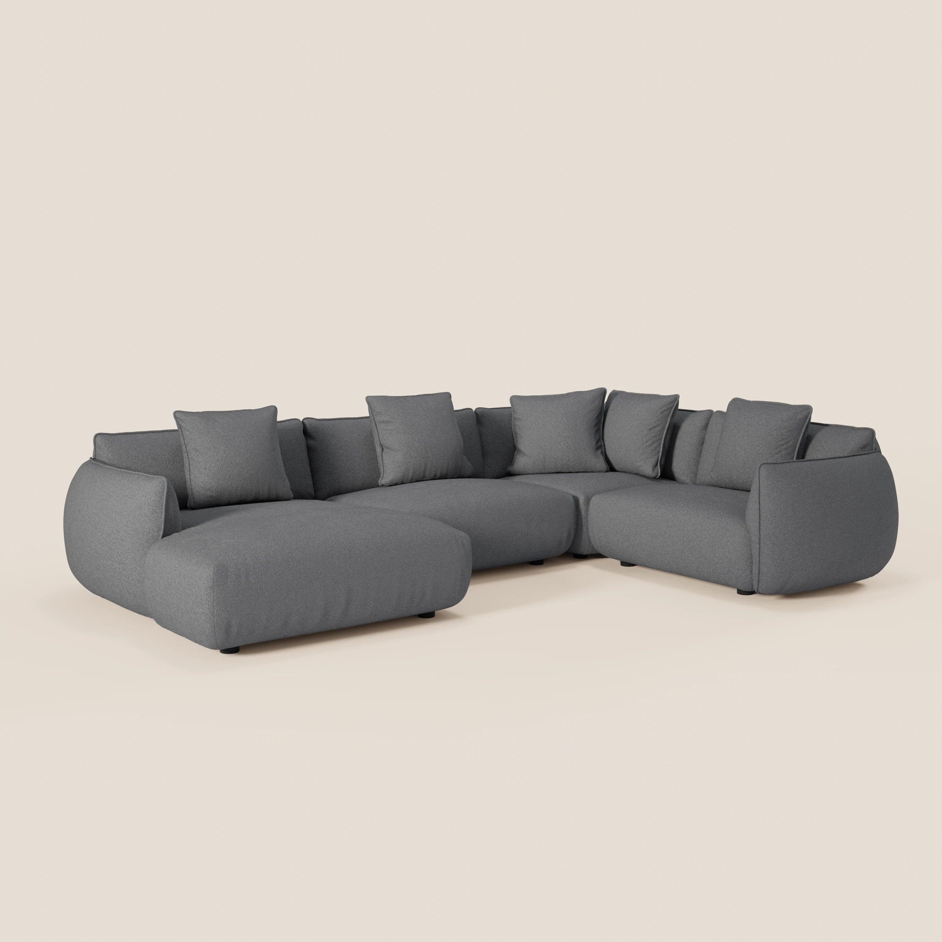 Il divano Nimbus angolare panoramico componibile con penisola e angolo di Divani.Store, rivestito in tessuto antimacchia grigio scuro t33, è caratterizzato da ampi e soffici cuscini e sette cuscini di schienale coordinati su sfondo beige chiaro.