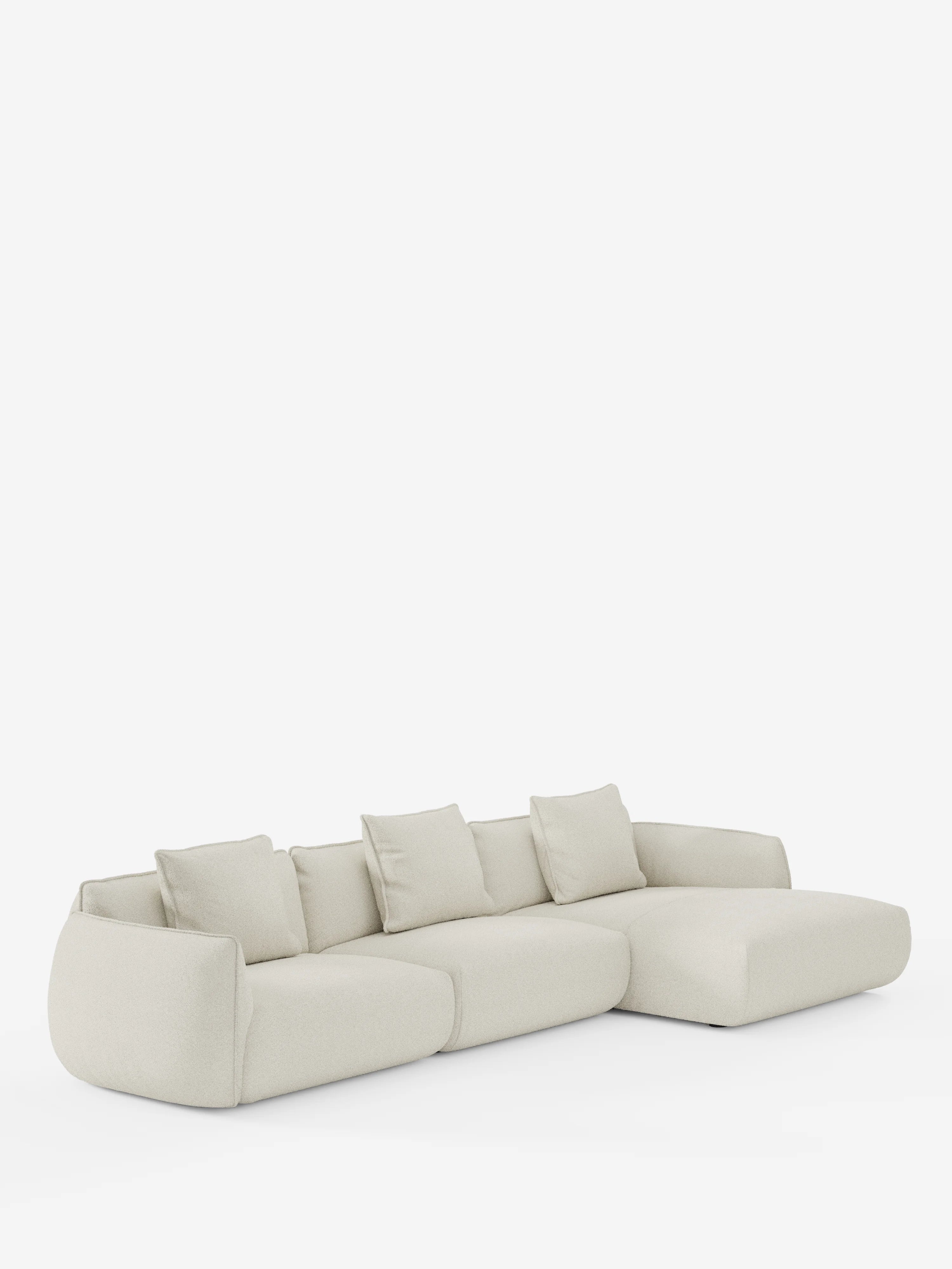 Il divano angolare con penisola componibile Nimbus di Divani.Store è un divano moderno color beige chiaro, realizzato in morbido tessuto effetto cotone smacchiabile T33, con chaise longue sul lato destro. Questo modello dal design contemporaneo include quattro cuscini dello schienale coordinati e presenta una silhouette bassa, arrotondata e minimalista che risalta su uno sfondo bianco a tinta unita.