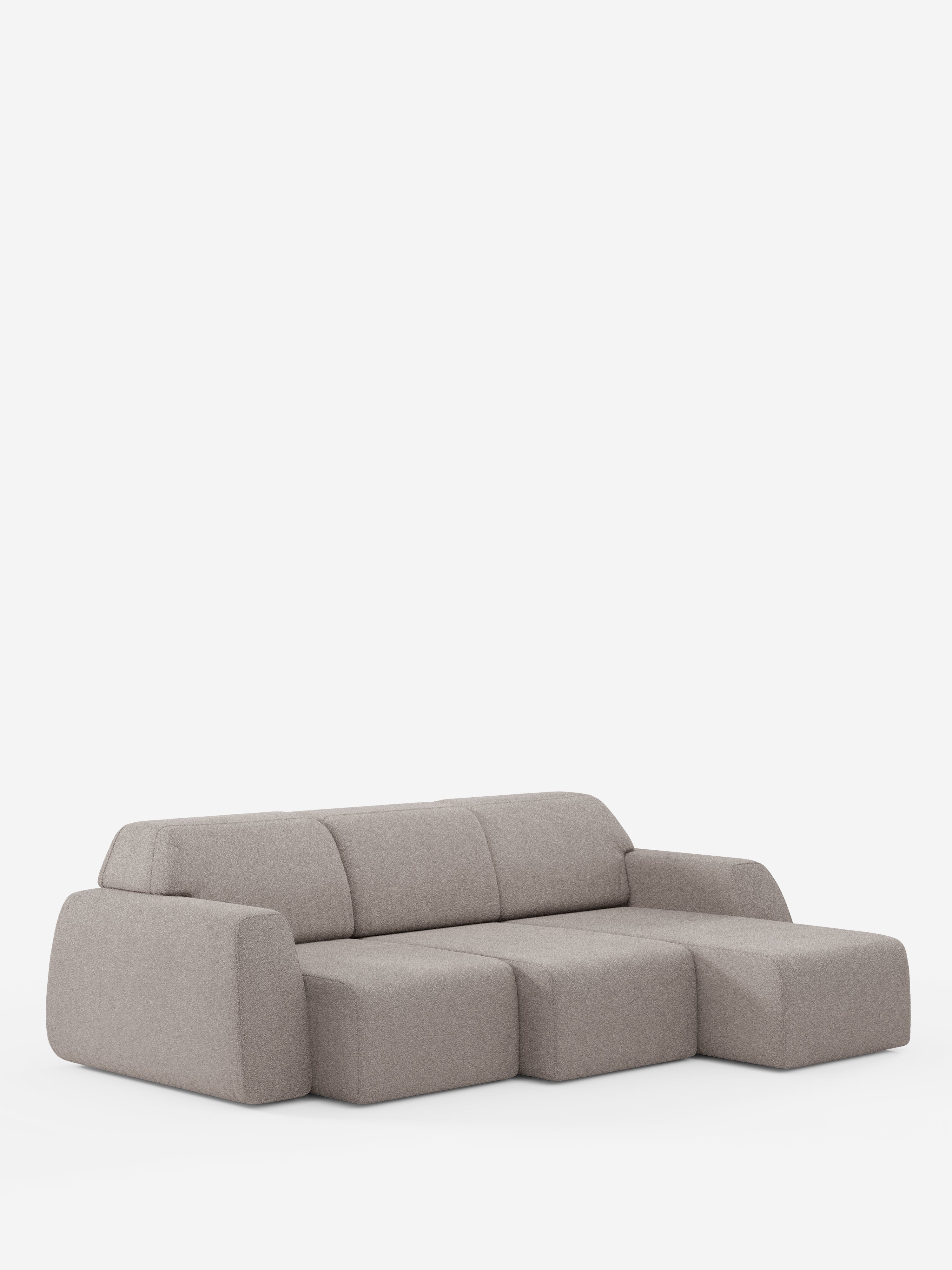 Un divano angolare Orbit contemporaneo, color grigio chiaro, con penisola reversibile e tutte le sedute allungabili, rivestito in tessuto smacchiabile effetto cotone T33 di Divani.Store, caratterizzato da braccioli bassi e arrotondati e da una chaise longue posizionata sulla destra, che si staglia su uno sfondo bianco senza cuciture. I suoi cuscini spessi e il design minimalista conferiscono a questo divano di alta gamma un aspetto morbido e accogliente.