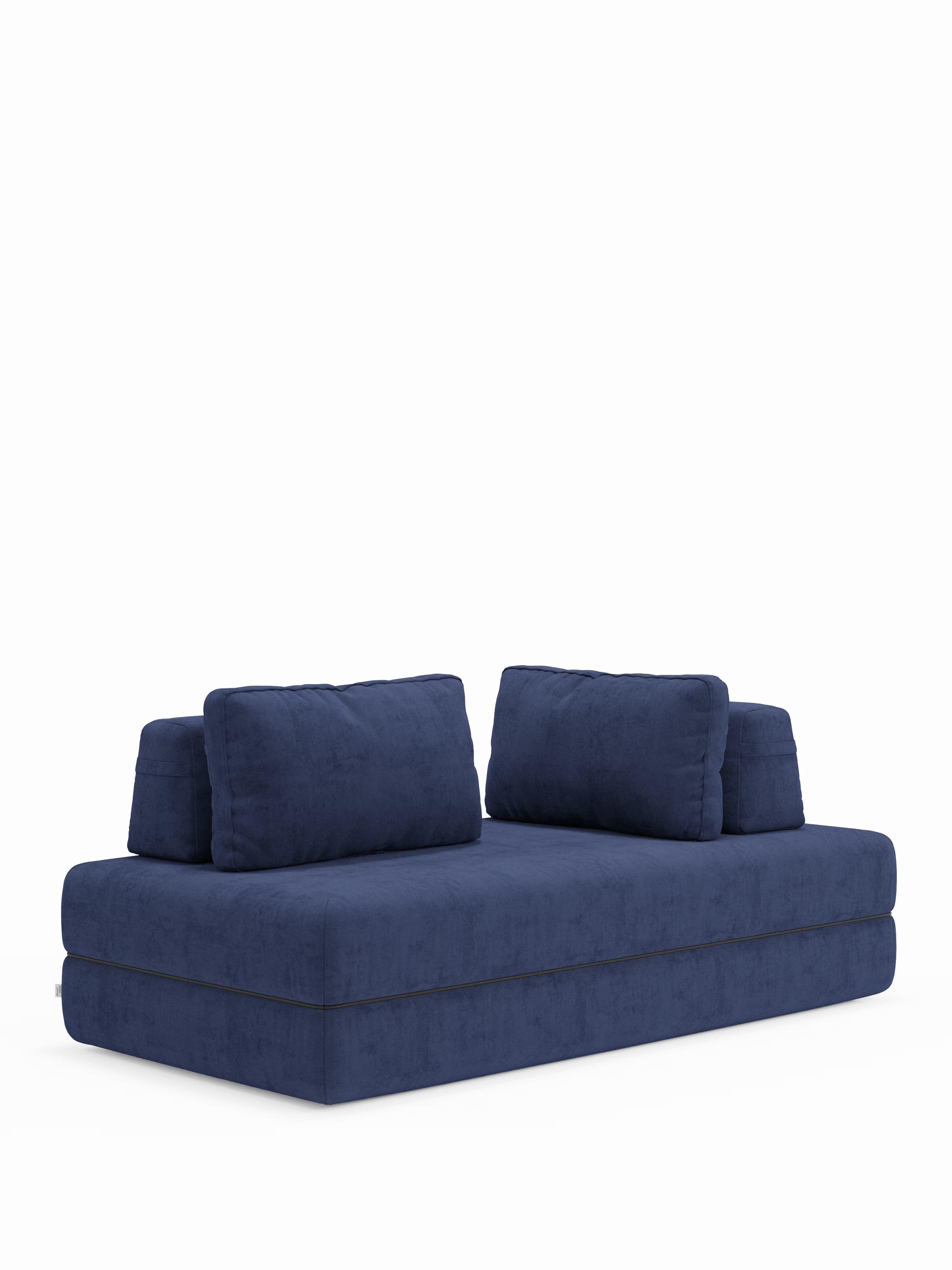 Un moderno divano letto matrimoniale a 2 posti Rift blu scuro di Divani.Store, caratterizzato da un profilo ribassato, due cuscini di seduta e quattro morbidi cuscini rettangolari per lo schienale, è posto su uno sfondo bianco a tinta unita. Il rivestimento morbido e vellutato conferisce a questo versatile divano un aspetto accogliente e invitante. Si trasforma facilmente in un ampio letto matrimoniale ed è dotato di un materasso in memory foam T31 alto 22 cm, per un comfort ottimale durante tutta la notte.