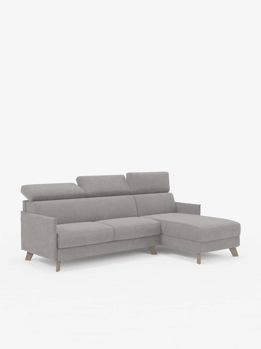Vi presentiamo il divano letto matrimoniale angolare Sole di Divani.Store, un moderno divano componibile in stile scandinavo rivestito in tessuto T23 grigio chiaro antimacchia. È dotato di poggiatesta regolabili, gambe in legno dall’elegante inclinazione e una chaise longue sul lato destro con una pratica penisola contenitore per uno spazio aggiuntivo. Lo sfondo bianco minimalista mette in risalto il divano come elemento centrale dell’immagine.