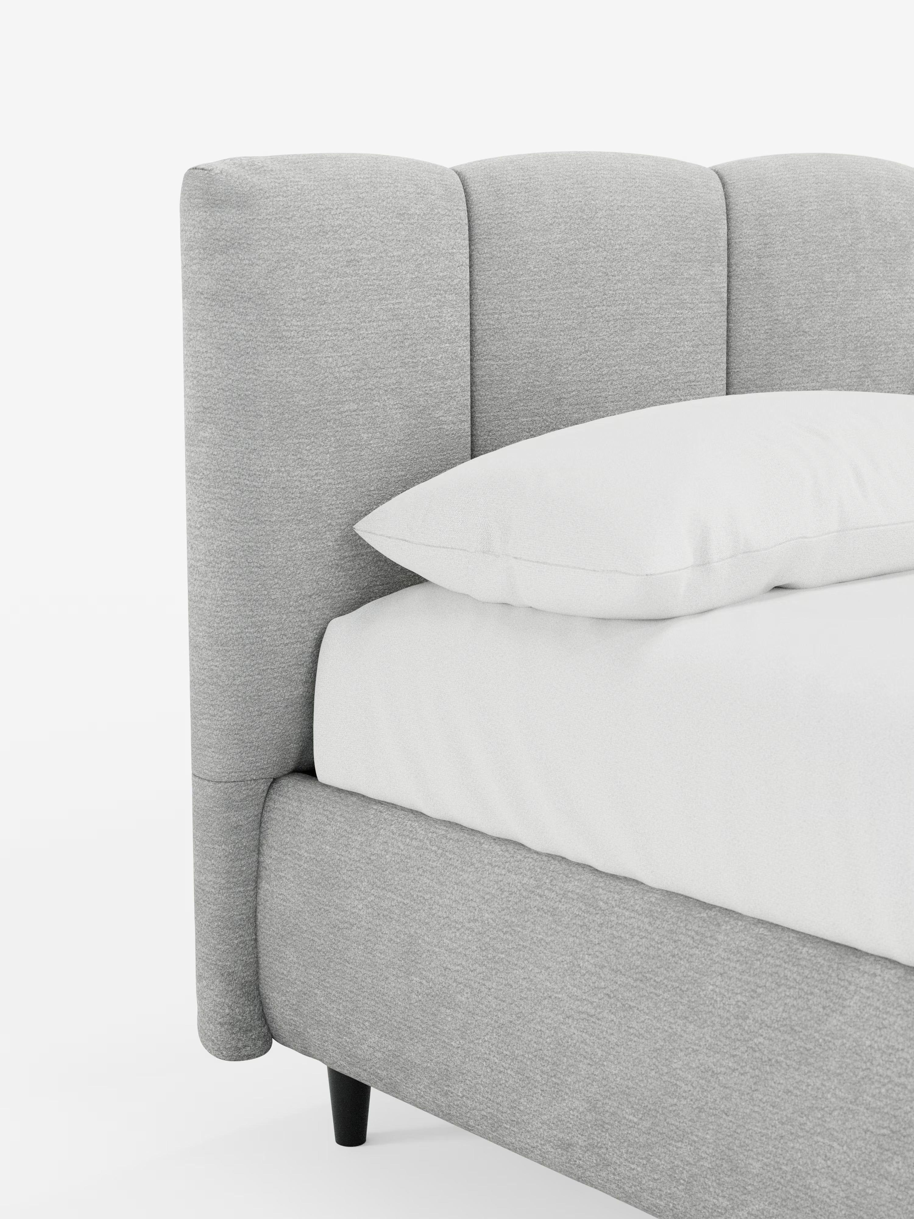 Un primo piano del letto imbottito ARKAM con contenitore e testiera a cuciture verticali di Letti.store ne mette in risalto il tessuto grigio chiaro, certificato Oeko-Tex®, e l’elegante testiera segmentata con cuciture verticali. Un cuscino bianco riposa sul letto rifatto con cura, con biancheria da letto candida e impeccabile, il tutto su uno sfondo bianco a tinta unita che mette in risalto lo stile shabby chic e il design sofisticato del letto.