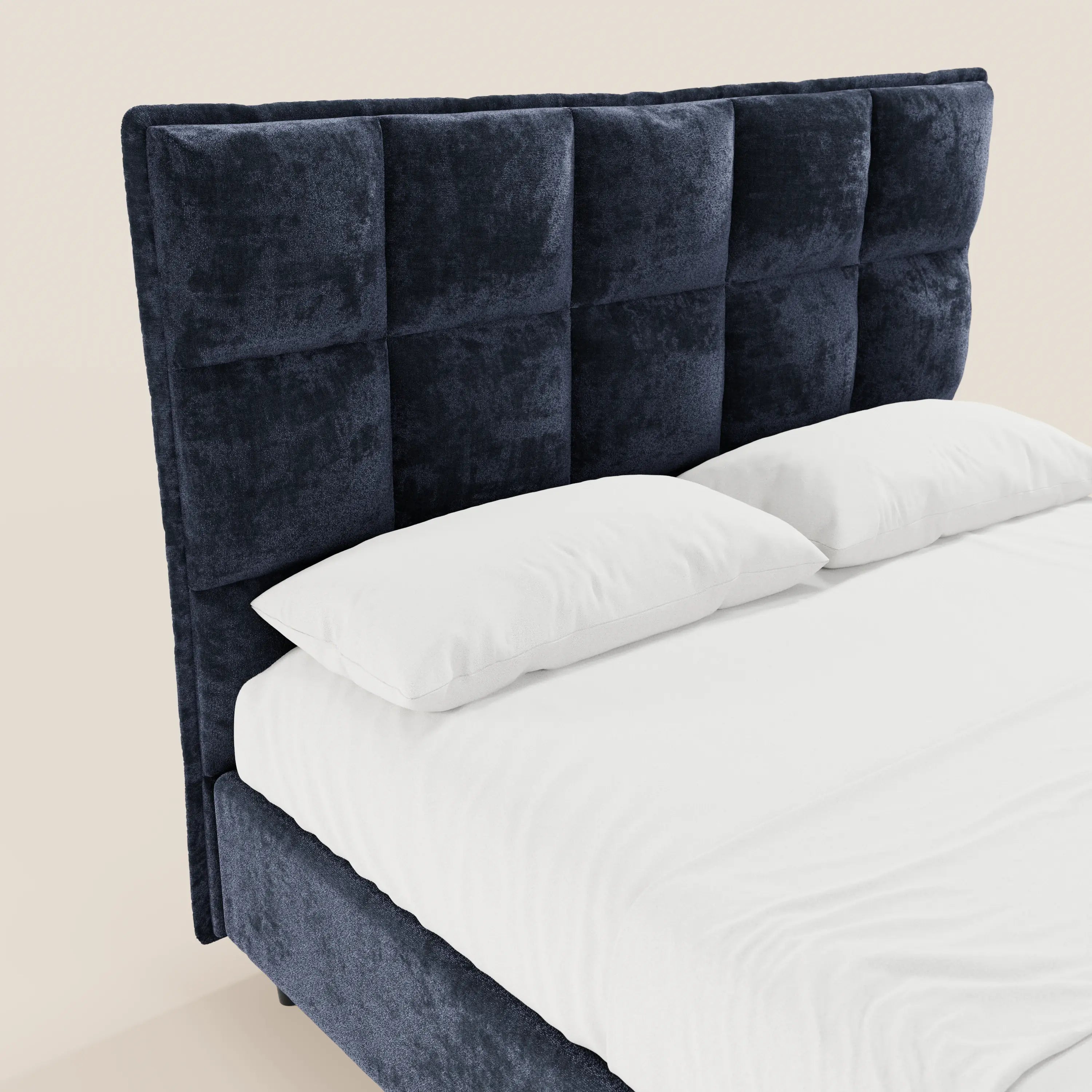 Il letto imbottito AURO di Letti.store presenta una testiera alta, blu navy, con finitura capitonné in ciniglia certificata Oeko-Tex®, lenzuola bianchissime e due cuscini bianchi che risaltano su uno sfondo beige chiaro.