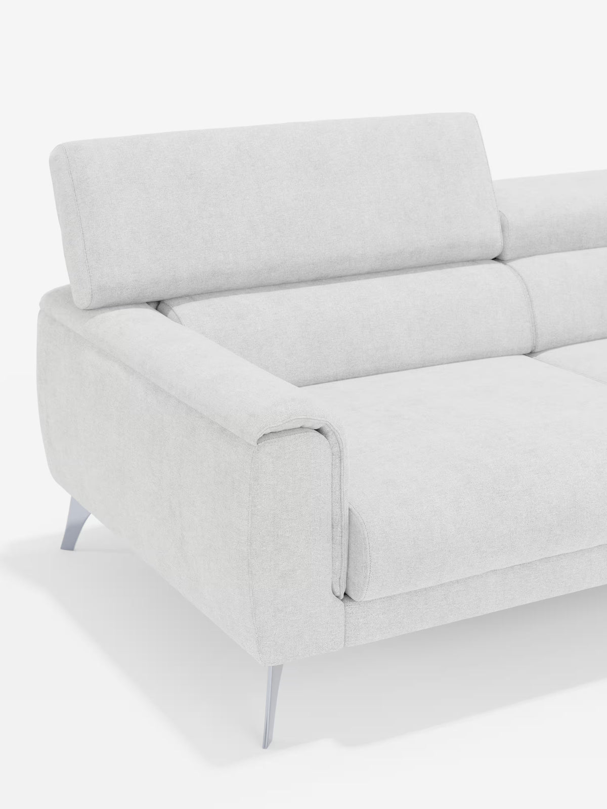 Un divano Caravaggio contemporaneo a 2 e 3 posti, colore grigio chiaro, di Divani.Store, caratterizzato da gambe in metallo, ampi braccioli imbottiti e poggiatesta regolabili e leggermente inclinati, rivestito in elegante tessuto T31 antimacchia. Esposto su uno sfondo bianco a tinta unita, sono visibili solo il lato sinistro e una parte della seduta.