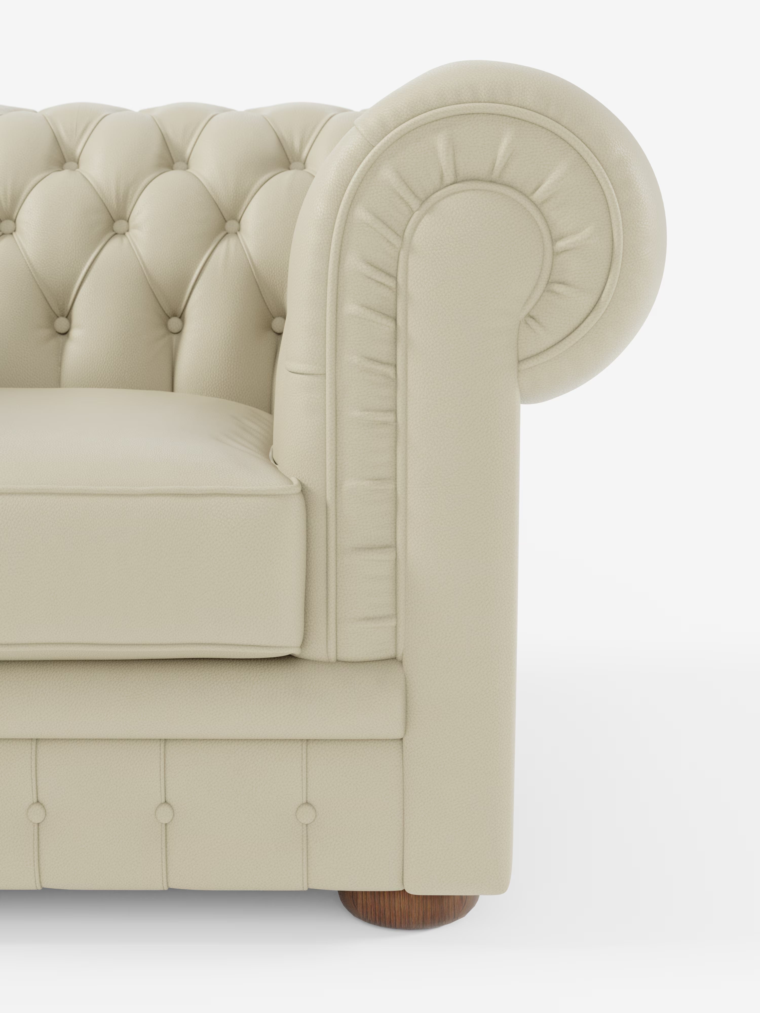 Primo piano di una poltrona Chester color crema in vera pelle spessorata con capitonné artigianale di Divani.Store, che mette in risalto il bracciolo arrotondato, i dettagli a bottoni, il cuscino con bordino e la gamba in legno: un pezzo iconico di arredamento di lusso su sfondo bianco.