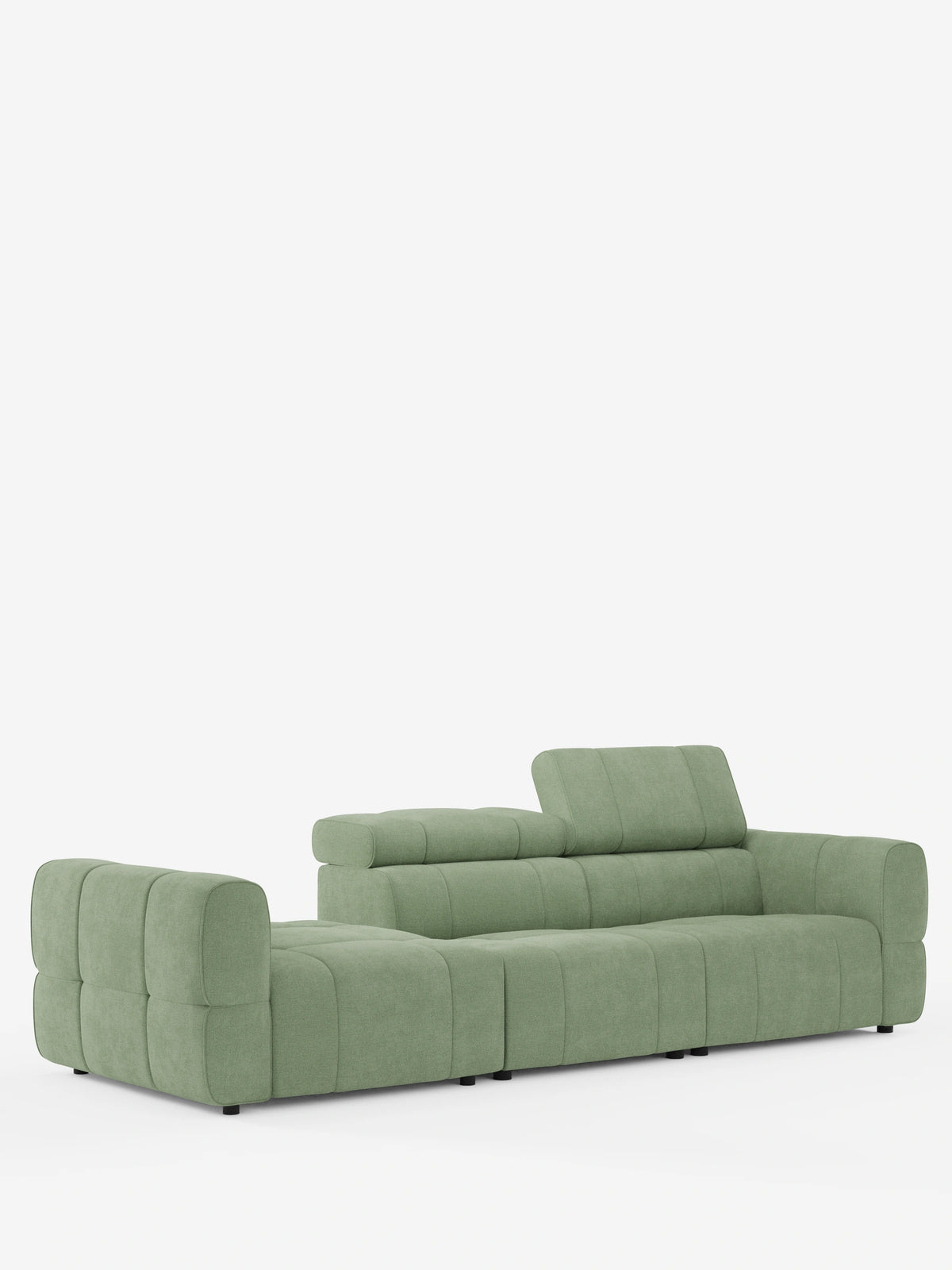 Un divano componibile Giotto Divano color verde salvia con terminale aperto - opzione relax elettrico in tessuto smacchiabile T23: divano modulare dal profilo basso e con ampi braccioli, caratterizzato da uno schienale rialzato e da cuscini trapuntati a griglia su sfondo bianco.