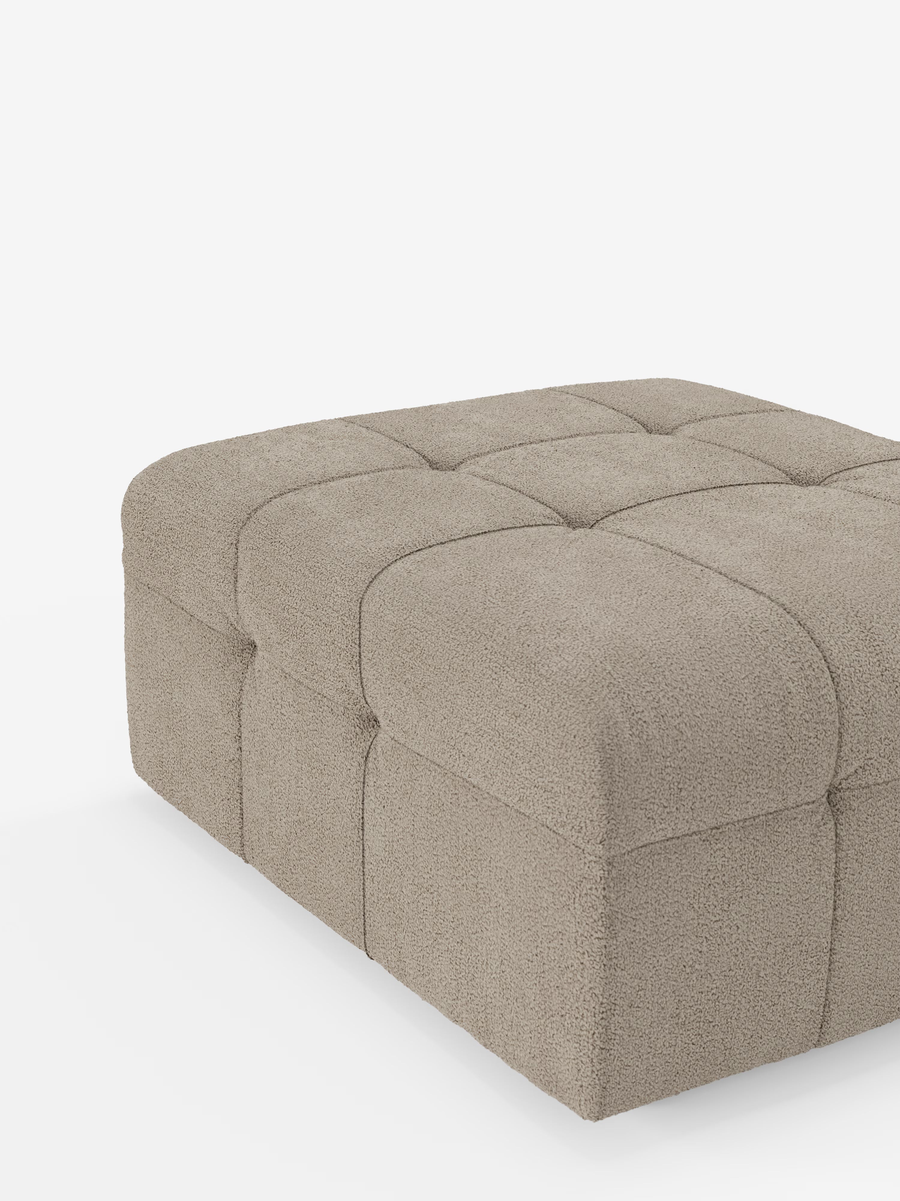 Una parte del pouf e modulo Mosaic in bouclé di Divani.Store è visibile su uno sfondo bianco. Questo pouf quadrato, che misura 96x77 cm, presenta un design capitonné rivestito in tessuto T21 resistente alle macchie, con distinti riquadri trapuntati sulla parte superiore e sui lati che creano un effetto morbido e imbottito.