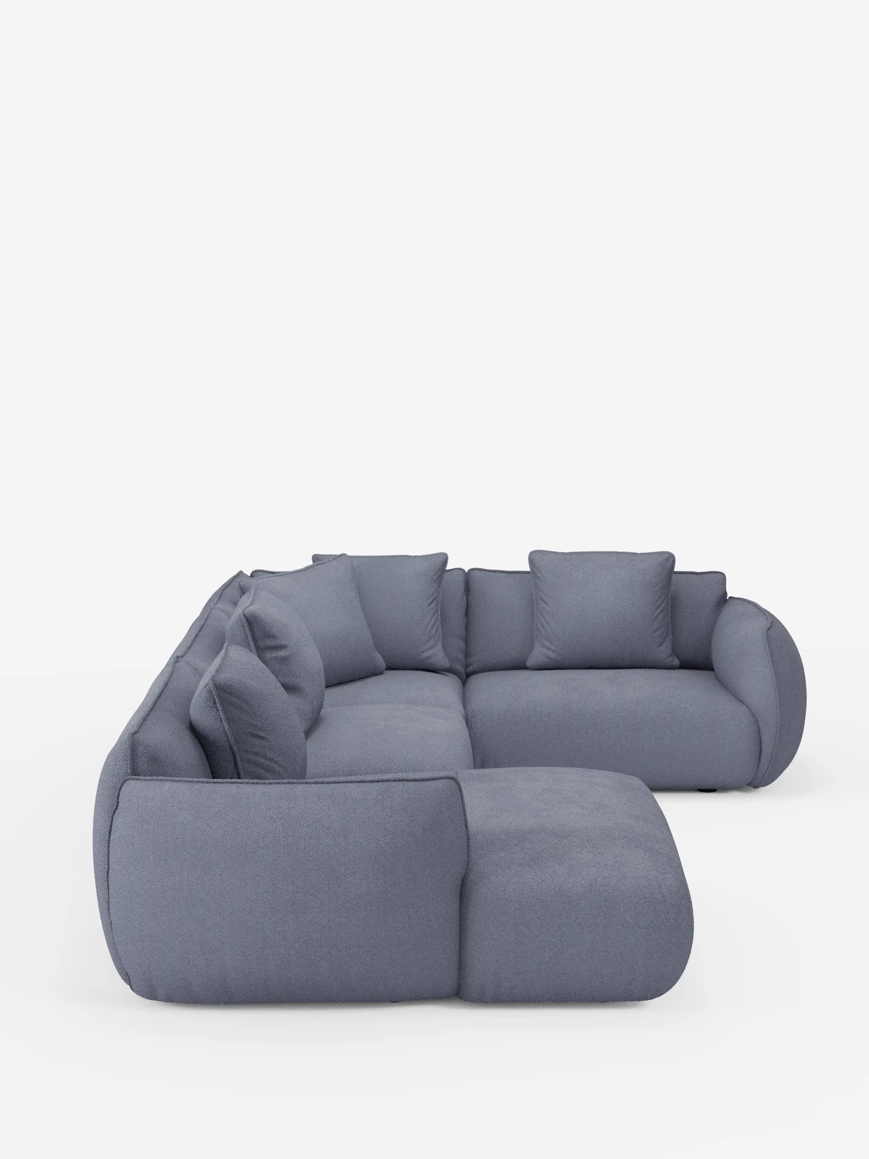 Il divano angolare panoramico componibile Nimbus con penisola e angolo in tessuto smacchiabile T33 di Divani.Store presenta morbidi cuscini arrotondati e sei cuscini quadrati coordinati, disposti con eleganza a forma di L su uno sfondo bianco a tinta unita. Questo divano moderno vanta braccioli e schienali morbidi e sinuosi che mettono in risalto la raffinatezza dell’artigianato italiano — orgogliosamente realizzato in Italia.