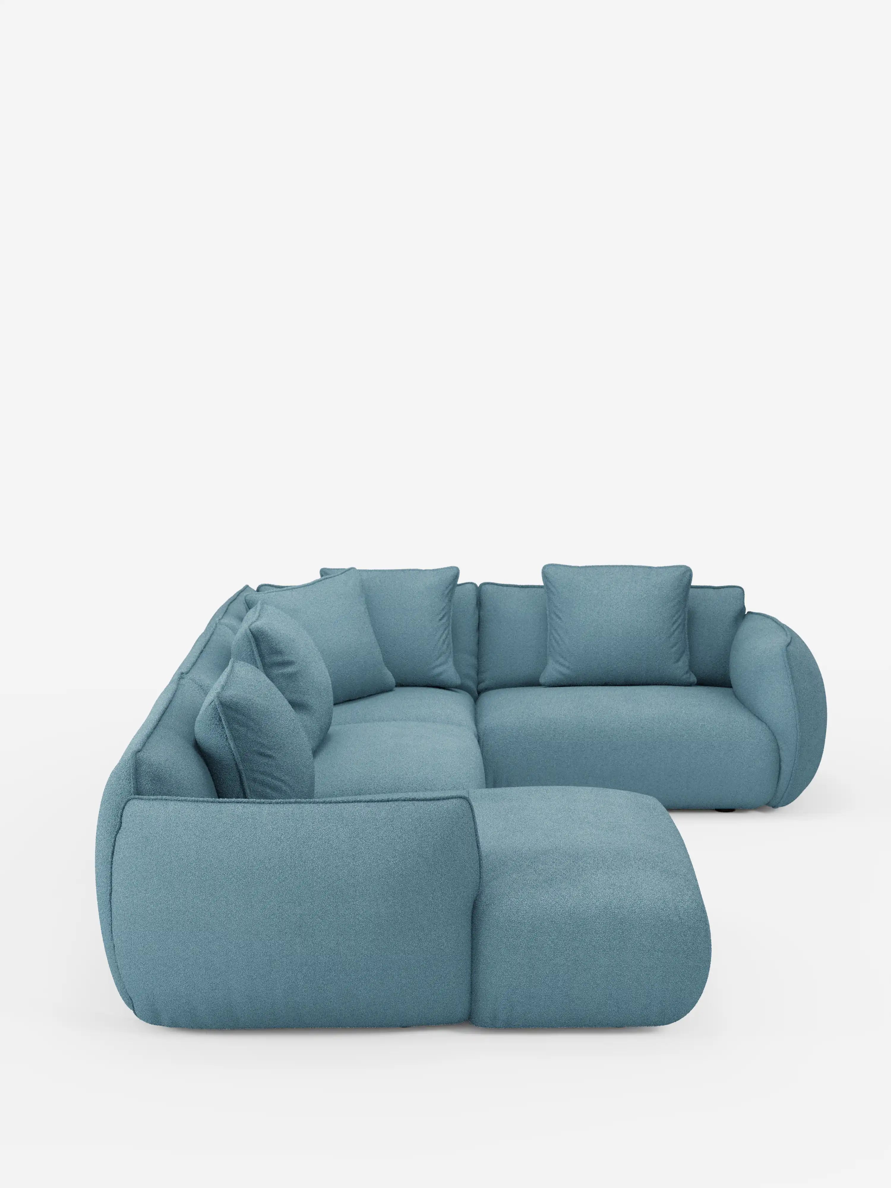 Il divano angolare panoramico componibile Nimbus con penisola e angolo in tessuto smacchiabile T33 di Divani.Store è un moderno divano componibile a L in tessuto color verde acqua, caratterizzato da bordi arrotondati e da morbidi e spessi cuscini con sette cuscini dello schienale abbinati, presentato su uno sfondo bianco a tinta unita.