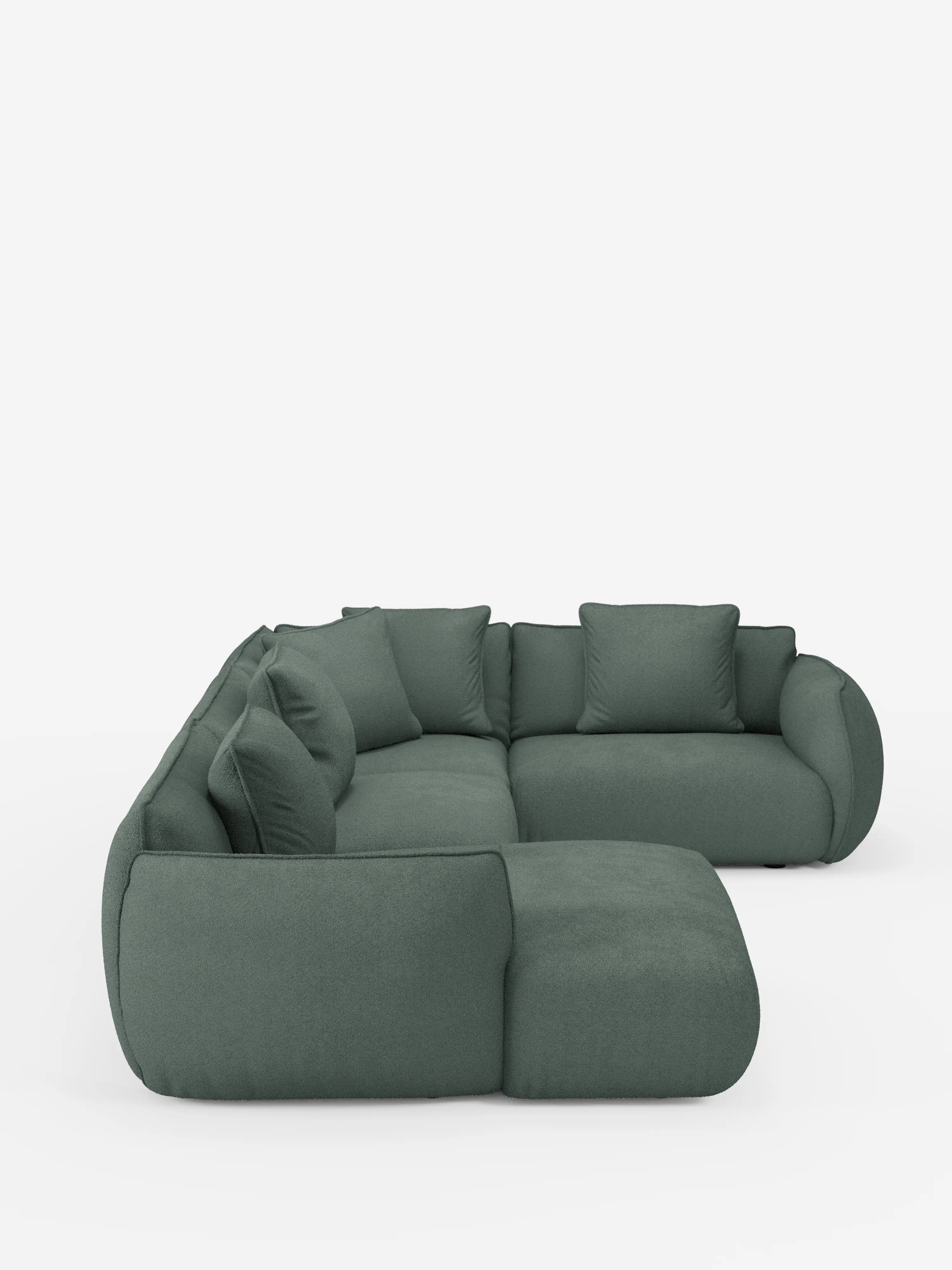 Un divano angolare panoramico componibile Nimbus in stile contemporaneo con penisola e angolo, rivestito in tessuto antimacchia T33 di Divani.Store, caratterizzato da un design modulare a forma di L con bordi arrotondati e morbidi cuscini, rivestito in tessuto verde tenue antimacchia, ripreso da una prospettiva laterale obliqua su uno sfondo bianco.