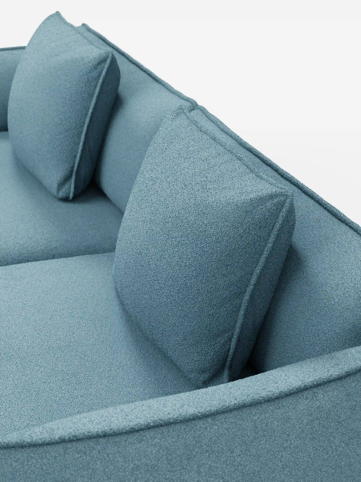 Primo piano del divano modulare e componibile Nimbus a 3 posti di Divani.Store, qui presentato in tessuto T33 effetto cotone smacchiabile di colore azzurro. Questo divano moderno da 250 cm è caratterizzato da due cuscini dello schienale quadrati e da un rivestimento morbido e leggermente ruvido. I bordi puliti e arrotondati ne esaltano il design minimalista, mentre lo sfondo bianco a tinta unita mette in risalto il colore e lo stile contemporaneo del divano.