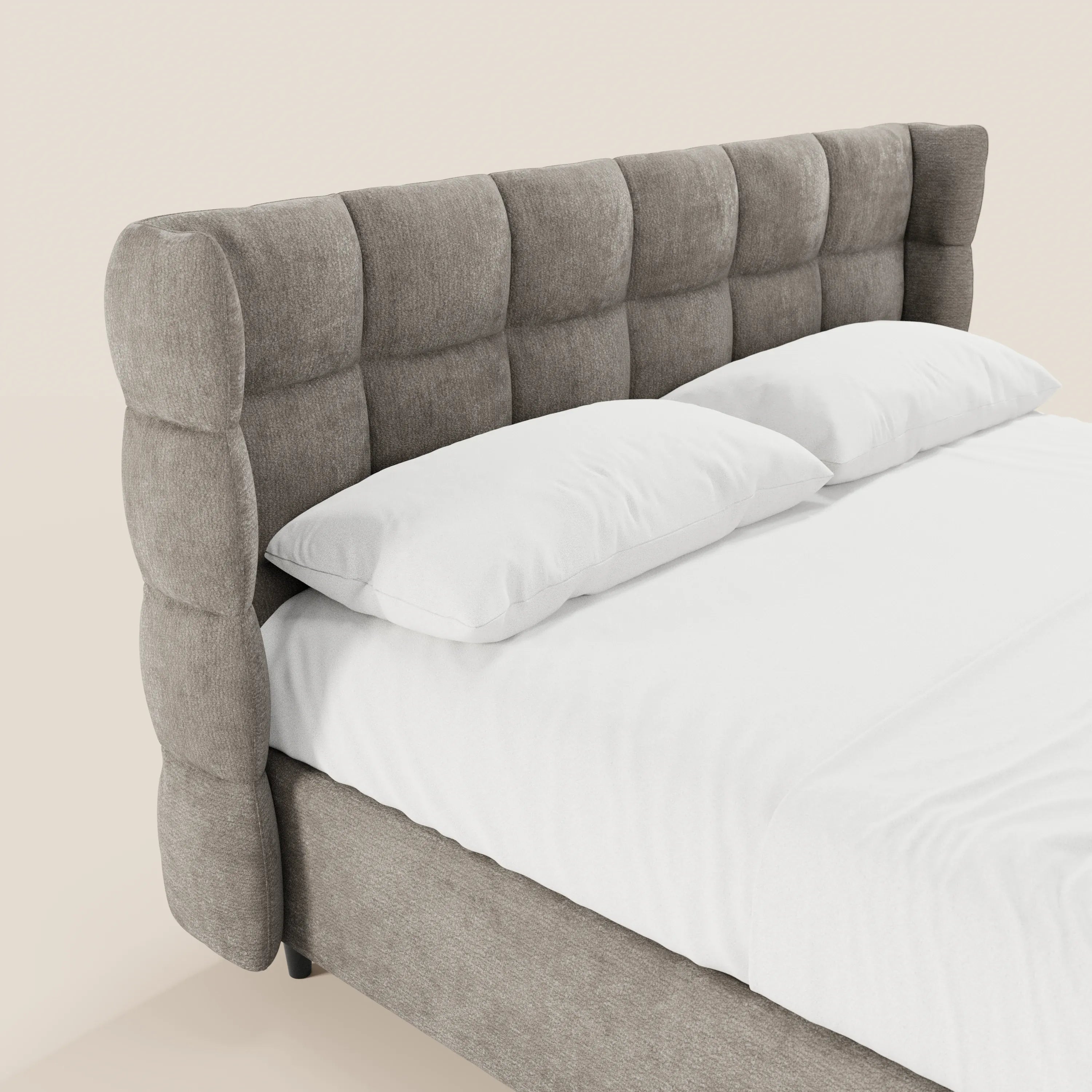 Un primo piano di RAGNAR di Letti.store, un letto contenitore imbottito con una testiera alta e avvolgente in stile capitonné, realizzata in un elegante tessuto certificato Oeko-Tex®, abbinato a biancheria da letto bianca su uno sfondo beige chiaro per un look moderno.