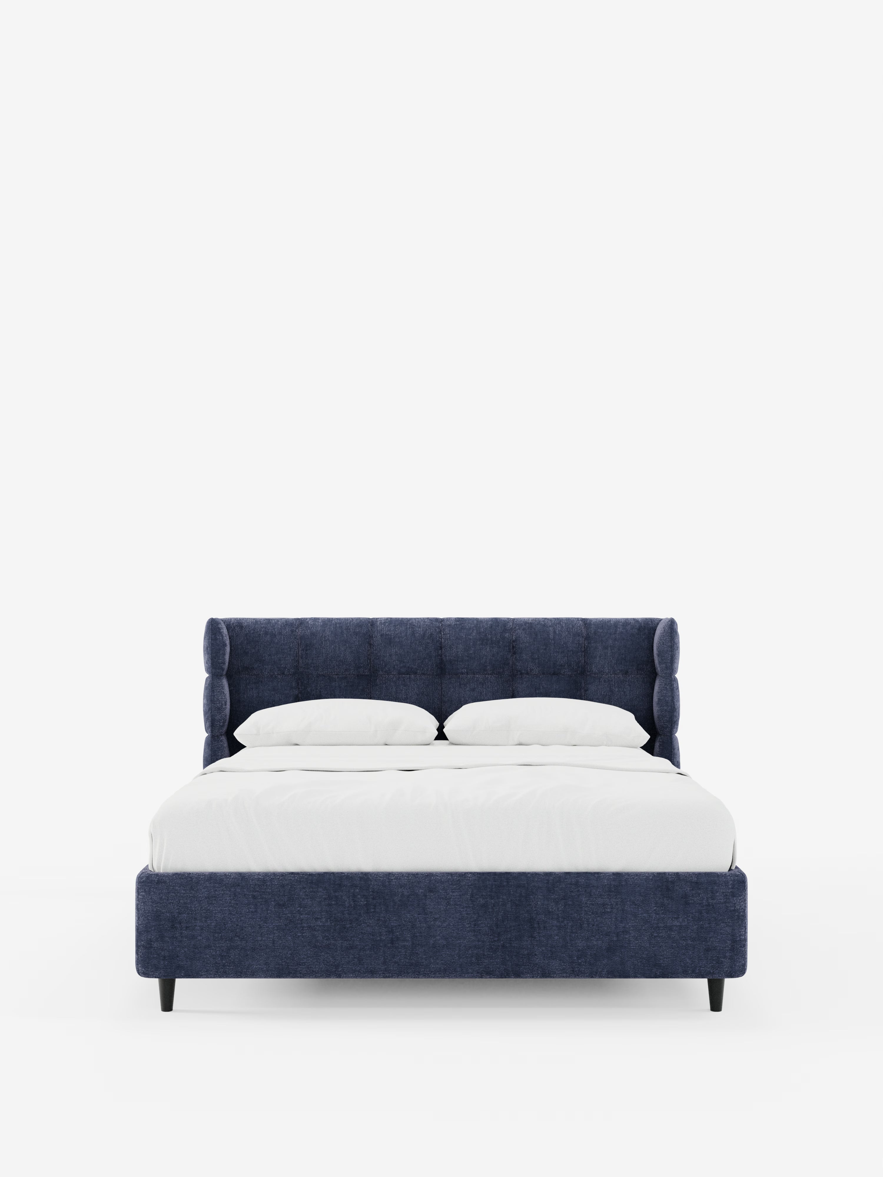 Una vista frontale del letto imbottito RAGNAR con contenitore e testiera capitonné avvolgente di Letti.store, caratterizzato da una struttura imbottita blu navy certificata Oeko-Tex® e da un’elegante testiera capitonné, rivestito con biancheria da letto bianca e due cuscini, su uno sfondo bianco a tinta unita.