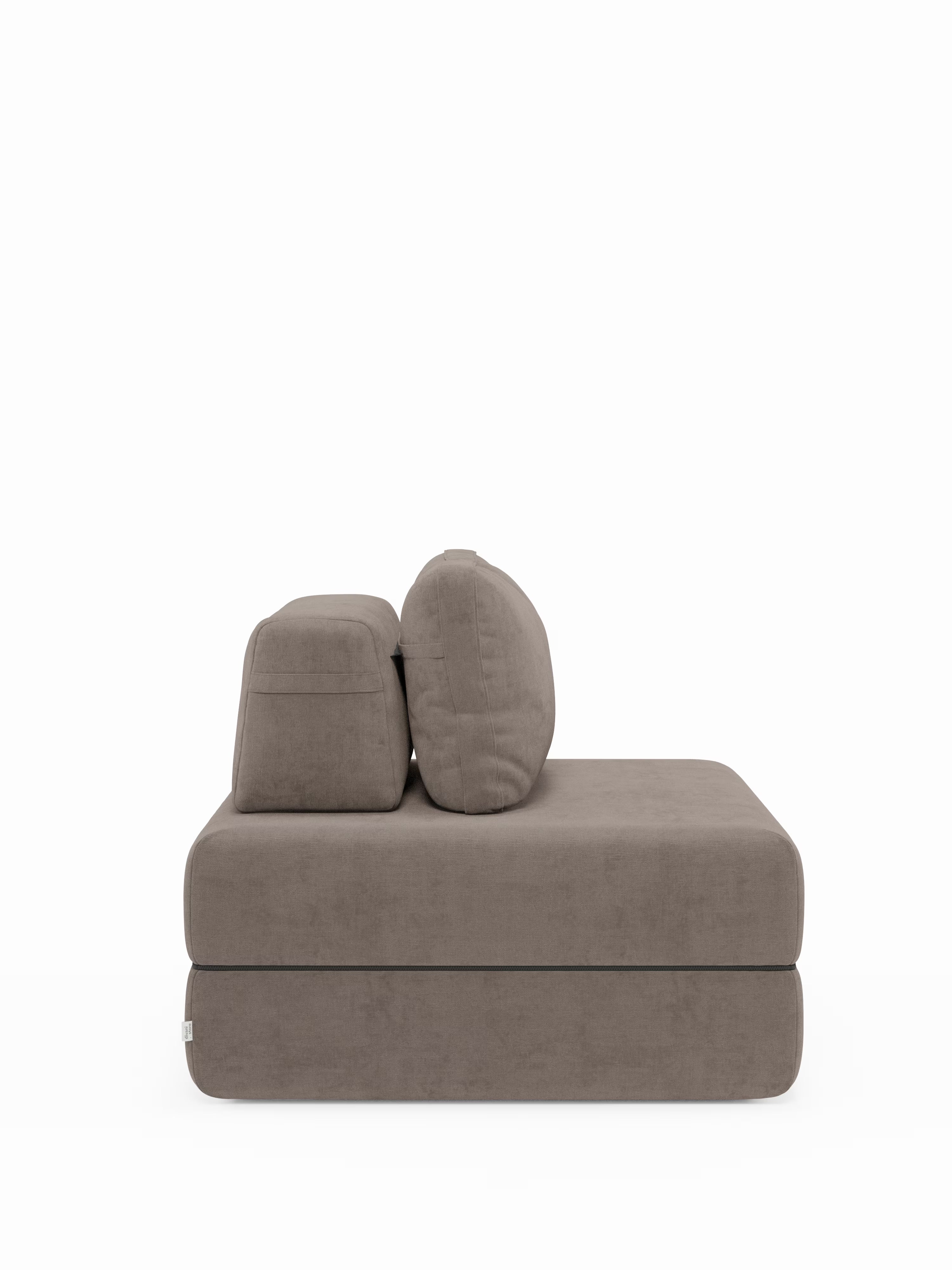La poltrona letto Rift con materasso alto 22 cm e memory foam di Divani.Store è un elemento modulare moderno e minimalista in tessuto color taupe, caratterizzato da cuscini spessi e da un unico schienale basso. Ritraito di profilo su uno sfondo bianco a tinta unita, questo versatile elemento è dotato di uno schienale mobile e di un rivestimento in tessuto T31 facile da pulire, che coniuga perfettamente stile e funzionalità per gli spazi abitativi contemporanei.