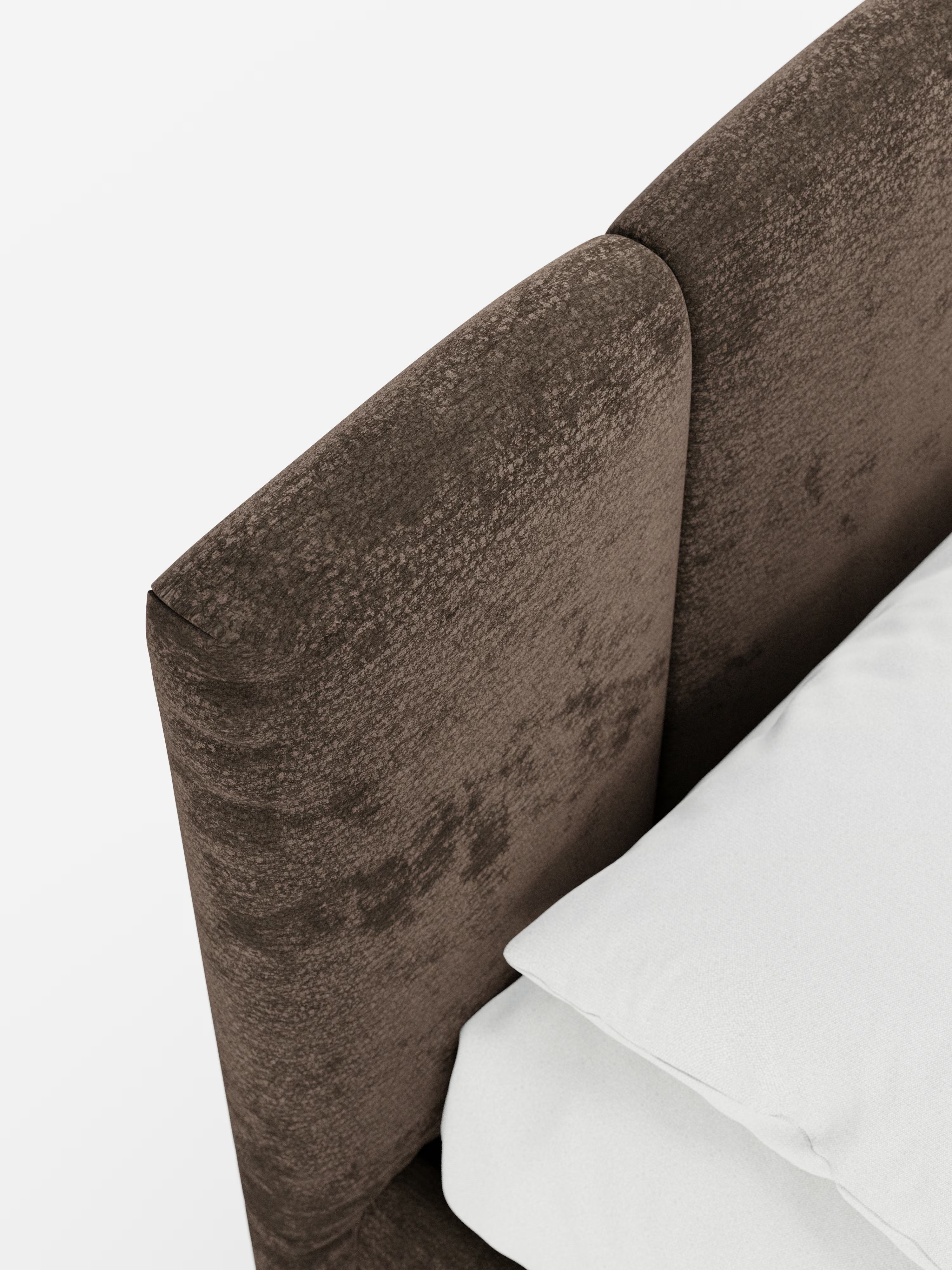 Primo piano dell'angolo superiore del letto imbottito ARKAM con contenitore e testiera a lavorazione verticale di Letti.store, che mette in risalto il tessuto marrone certificato Oeko-Tex® e la testiera in stile shabby chic con cuciture verticali; nell'angolo in basso a destra, su uno sfondo bianco a tinta unita, sono parzialmente visibili un cuscino bianco e la biancheria da letto.